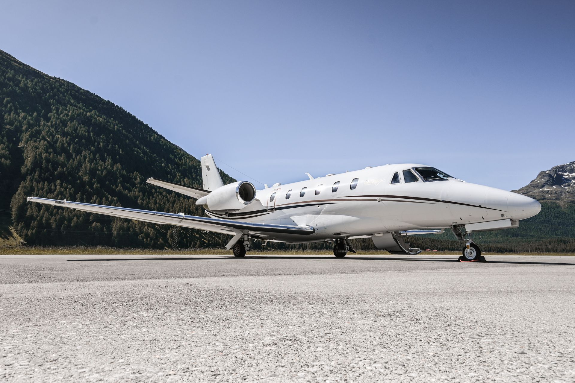 White private jet on a runway with mountains in the background