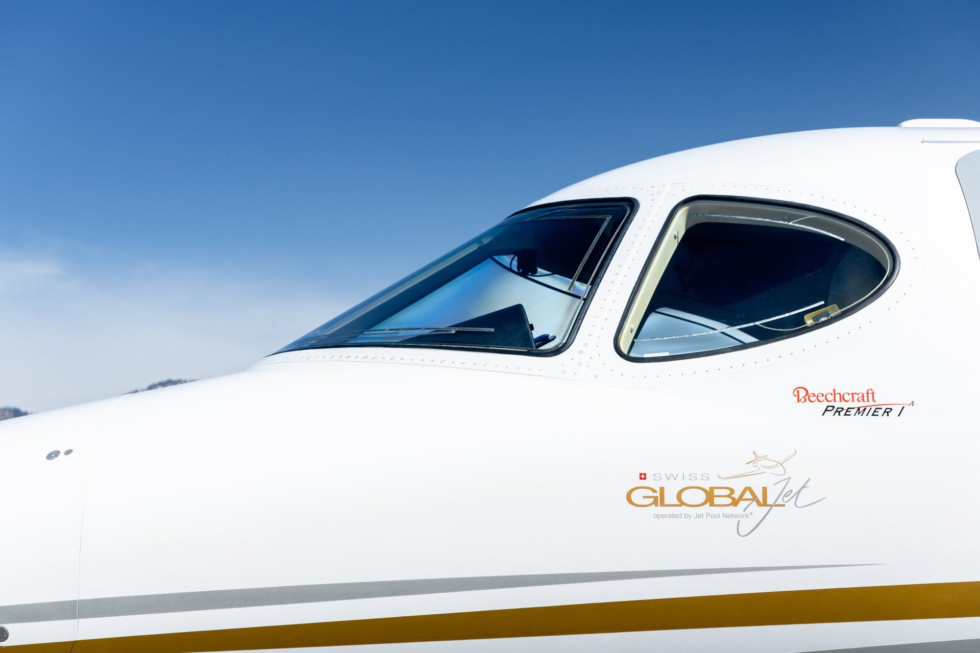 Close-up of a white private jet cockpit against a clear blue sky