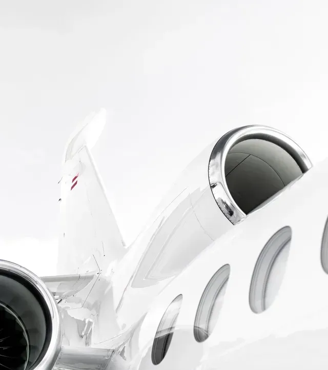Close-up of a white private jet with visible engine and cabin windows on a bright background