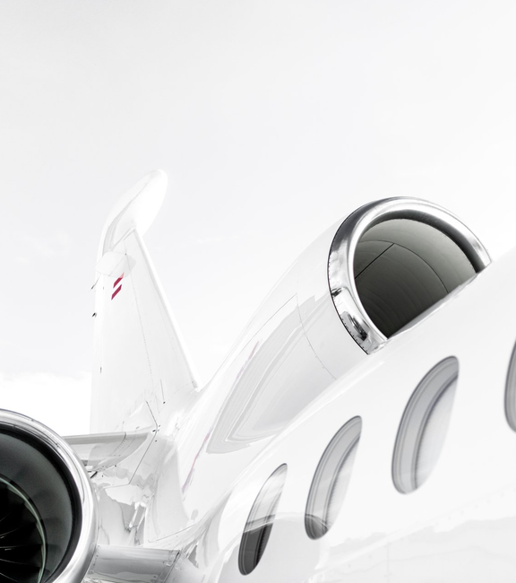 Close-up of a white private jet with cockpit windows and jet engines against a bright background