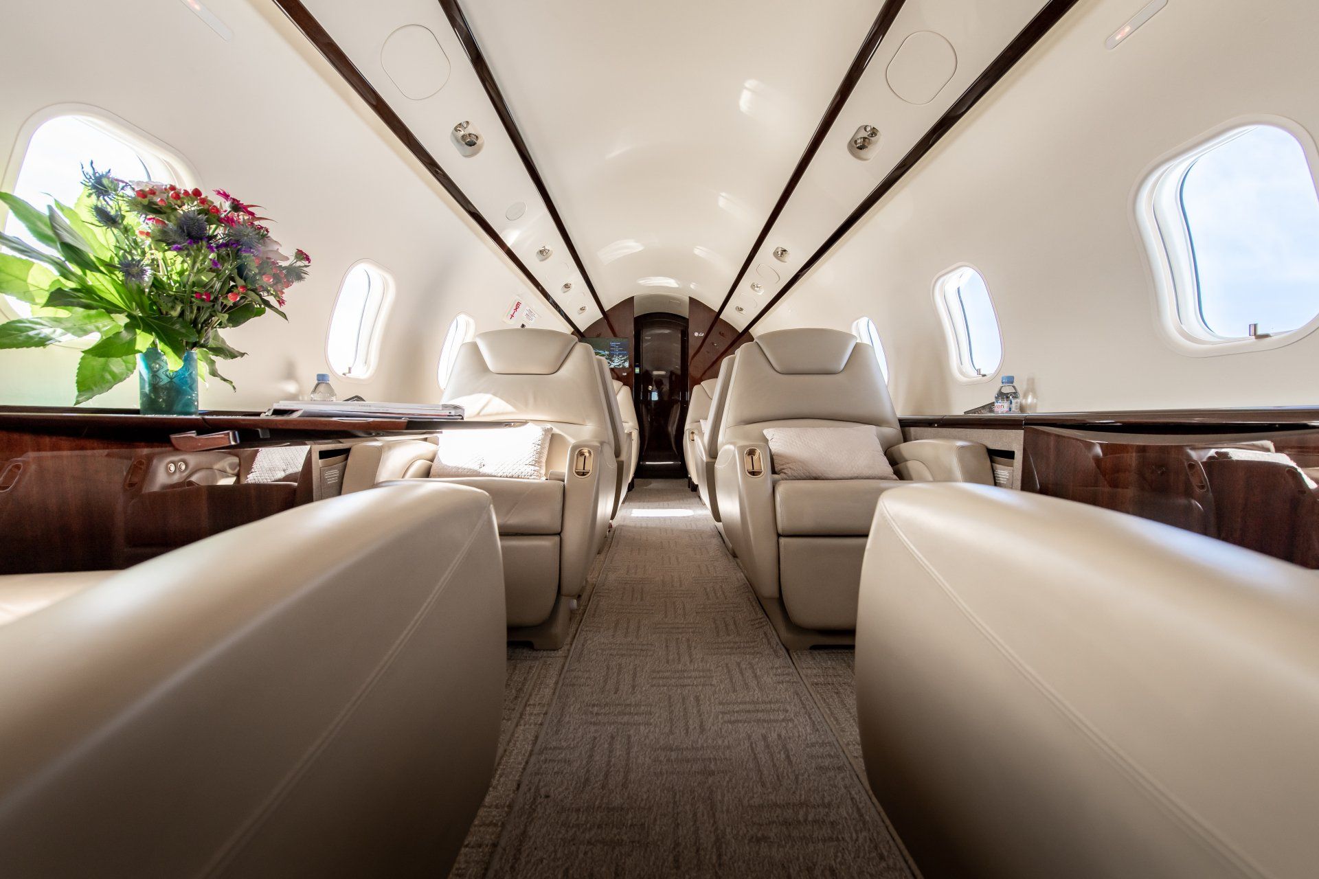 Luxurious private jet cabin with cream leather seats and a flower arrangement