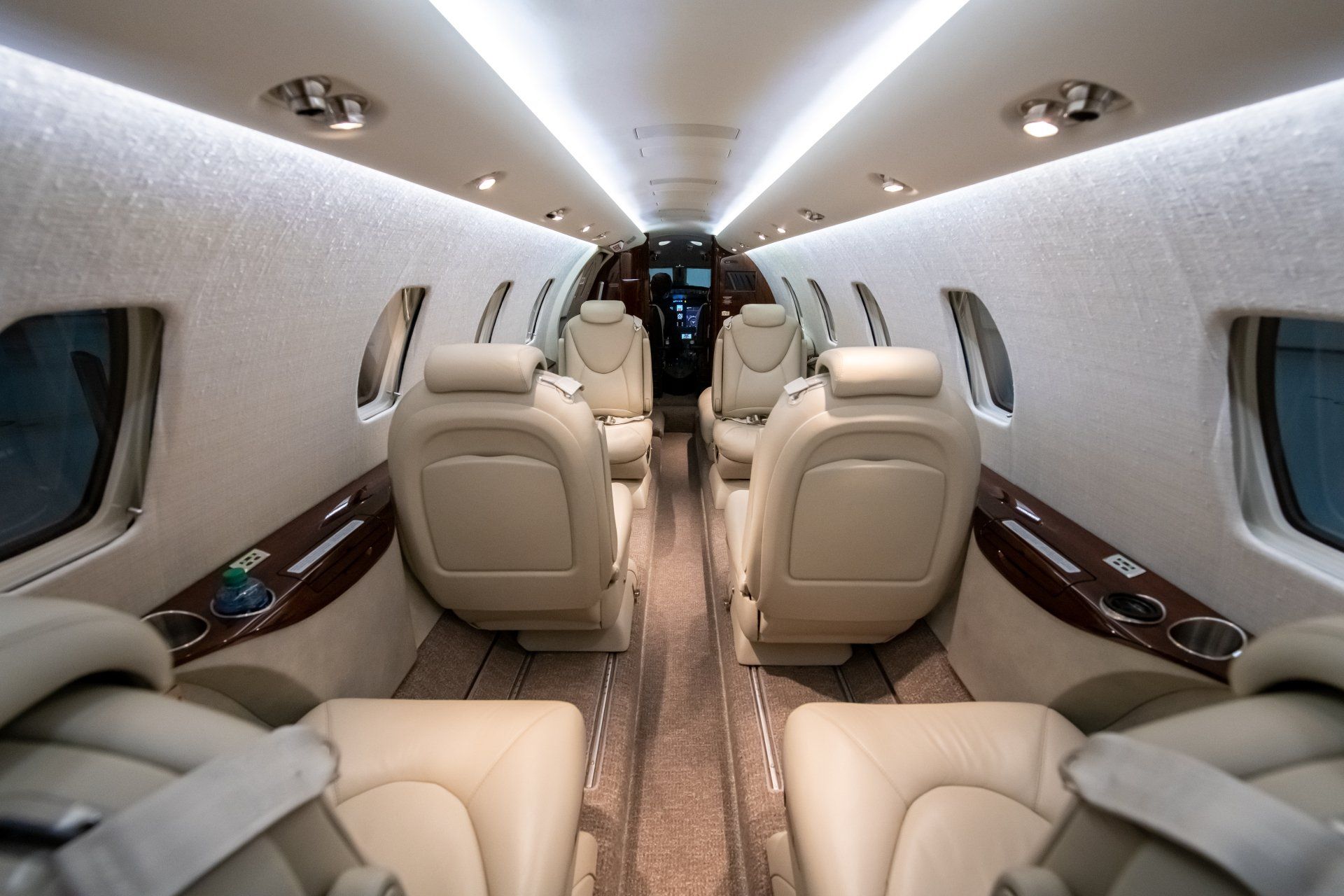 Luxurious private jet cabin with beige leather seats and polished wood trim