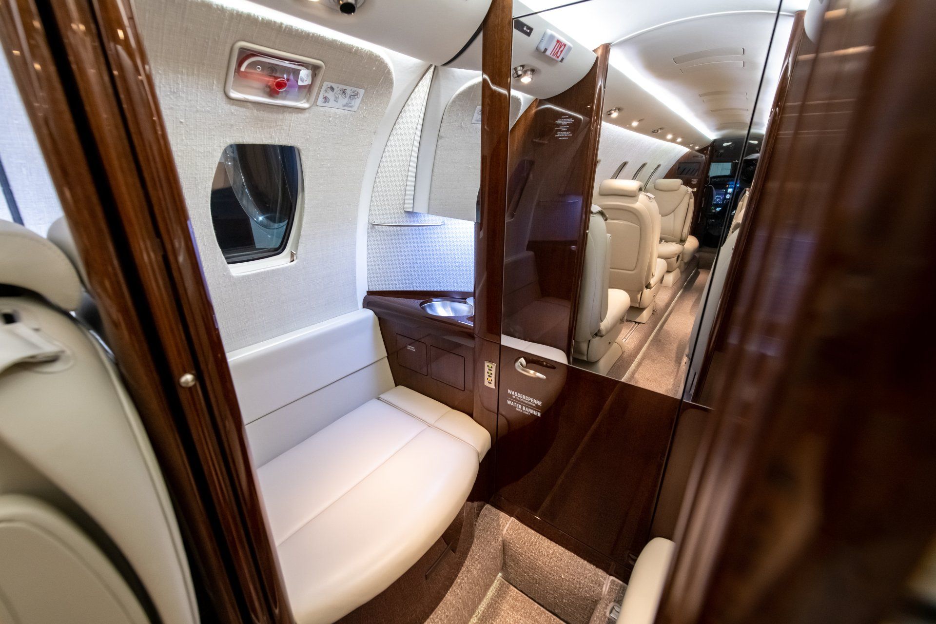 Luxurious private jet cabin with white leather seats and wood-paneled interior views.