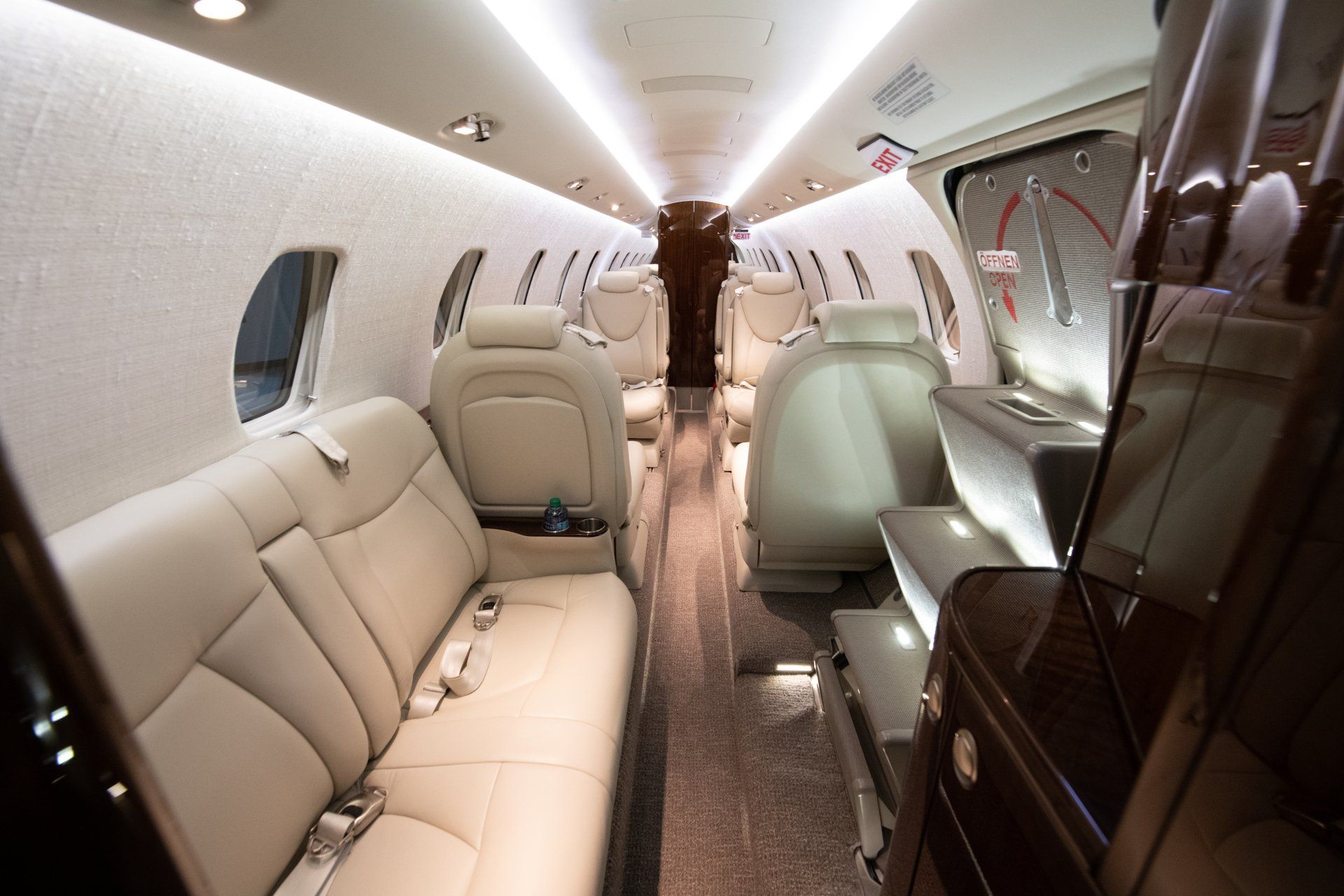 Luxurious private jet cabin with beige leather seats and polished wood paneling