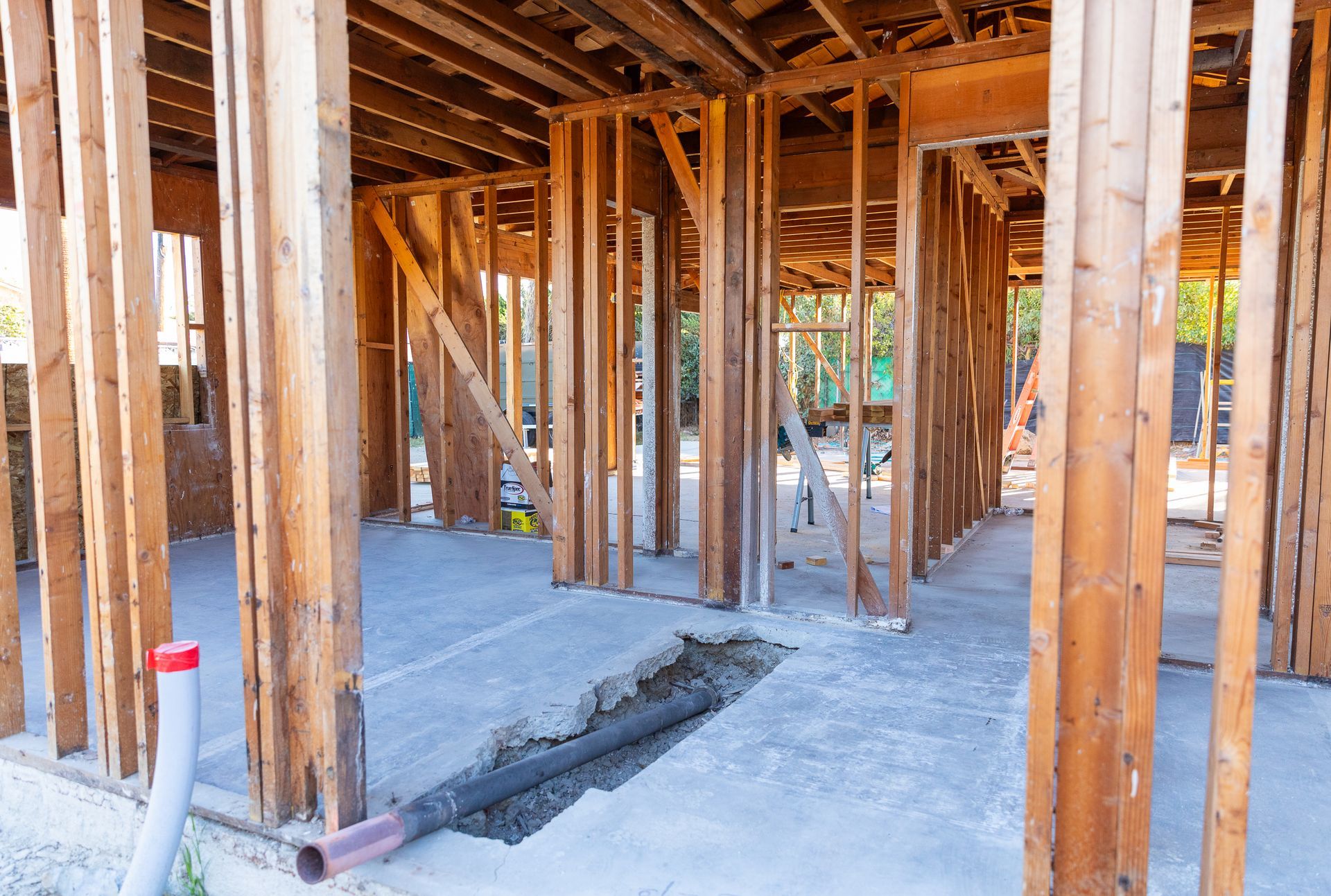 A house is being built with wooden beams and a hole in the ground.