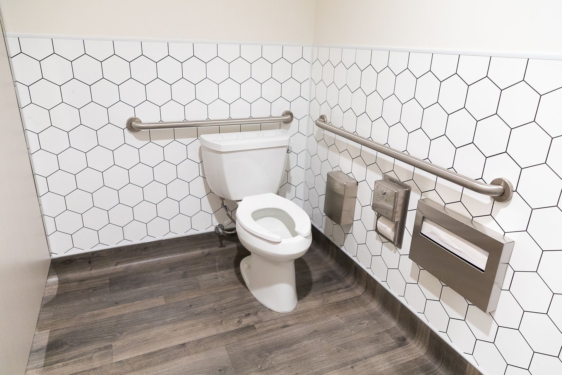 Accessible restroom with toilet, grab bars, and tiled walls in a clean, modern stall