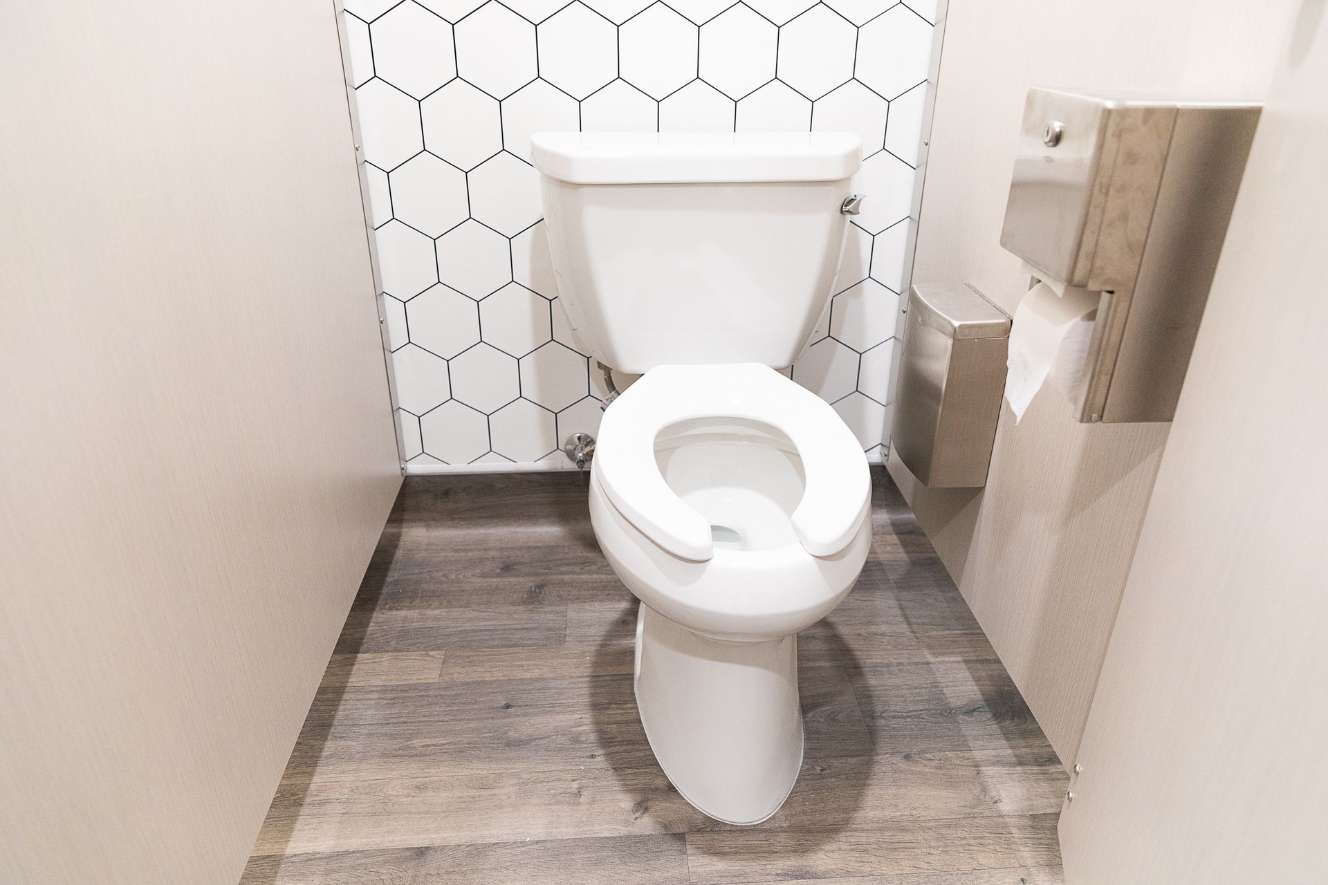 Public restroom with toilet, hexagonal wall tile, and gray flooring