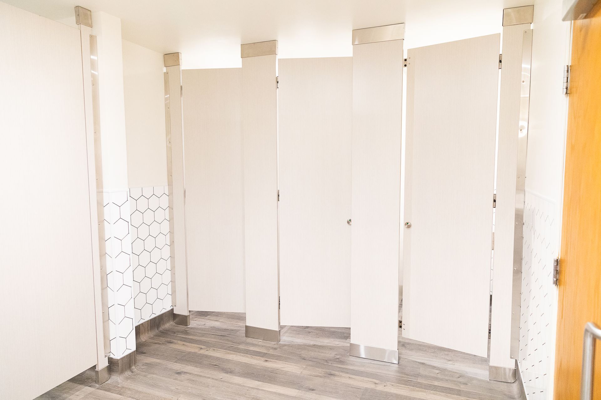 Empty public restroom with white stall doors and gray tile floor