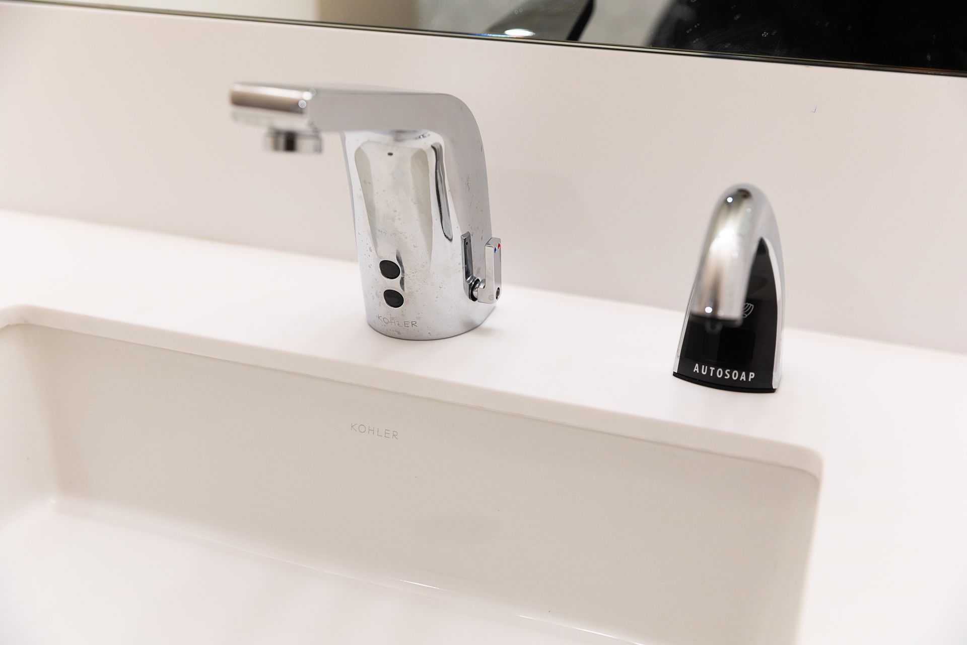 Chrome faucet and soap dispenser on a white bathroom sink countertop