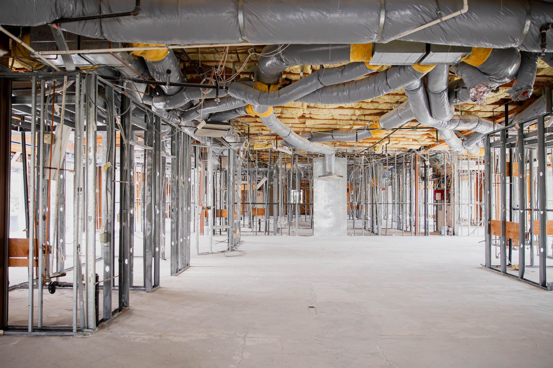 A building under construction with a lot of pipes coming out of the ceiling.