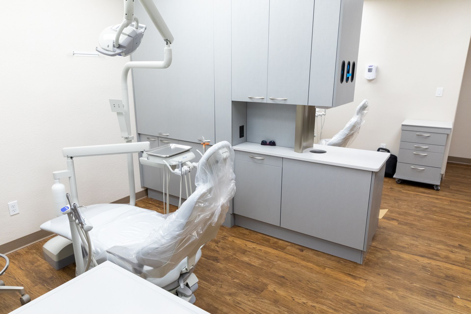 A dental office with a dental chair and cabinets.