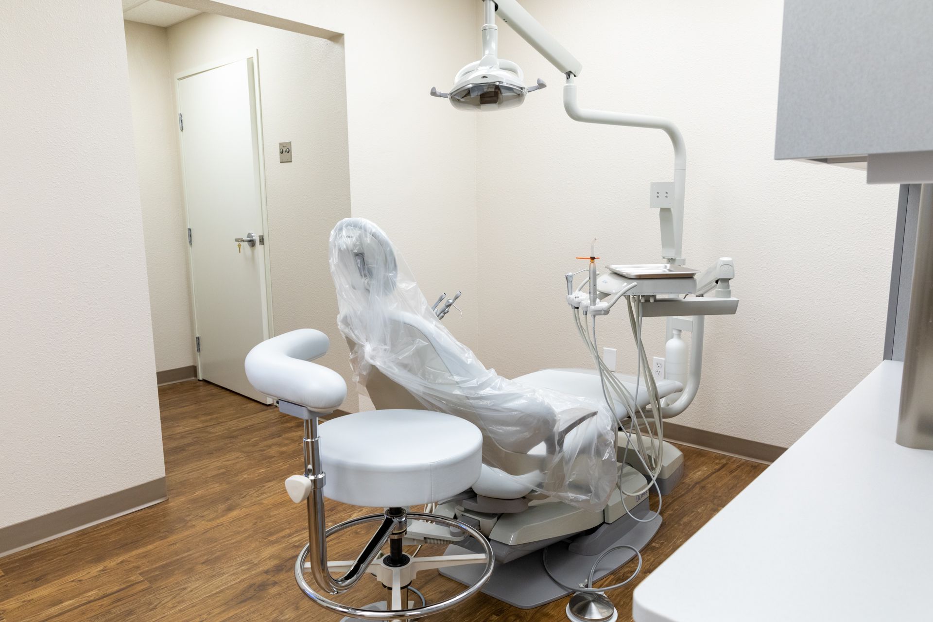 A dental office with a dental chair and a stool.
