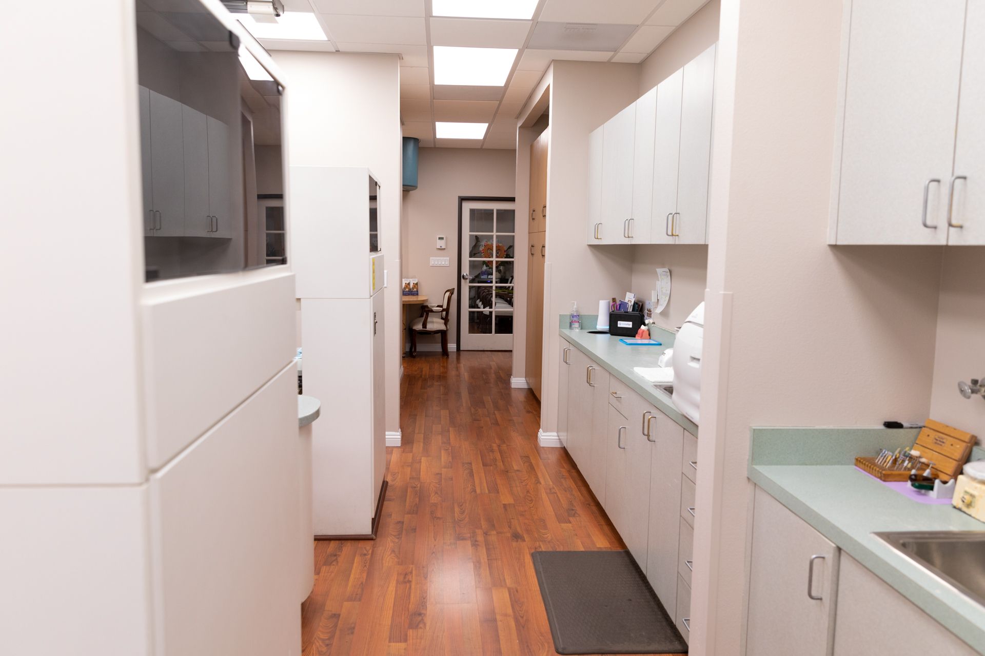 A kitchen with white cabinets and a sink in a dental office.