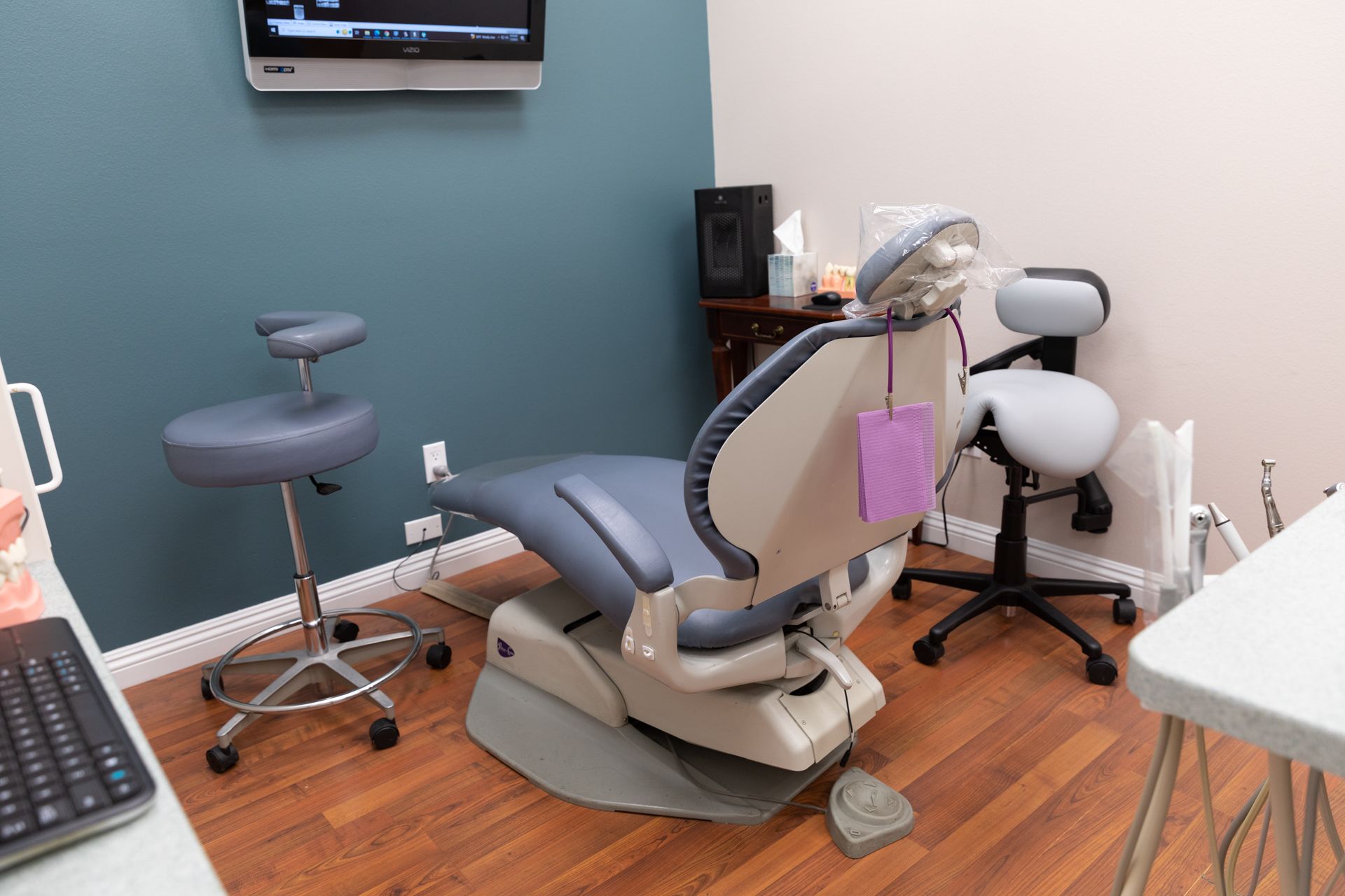 A dental office with a dental chair and a television on the wall.