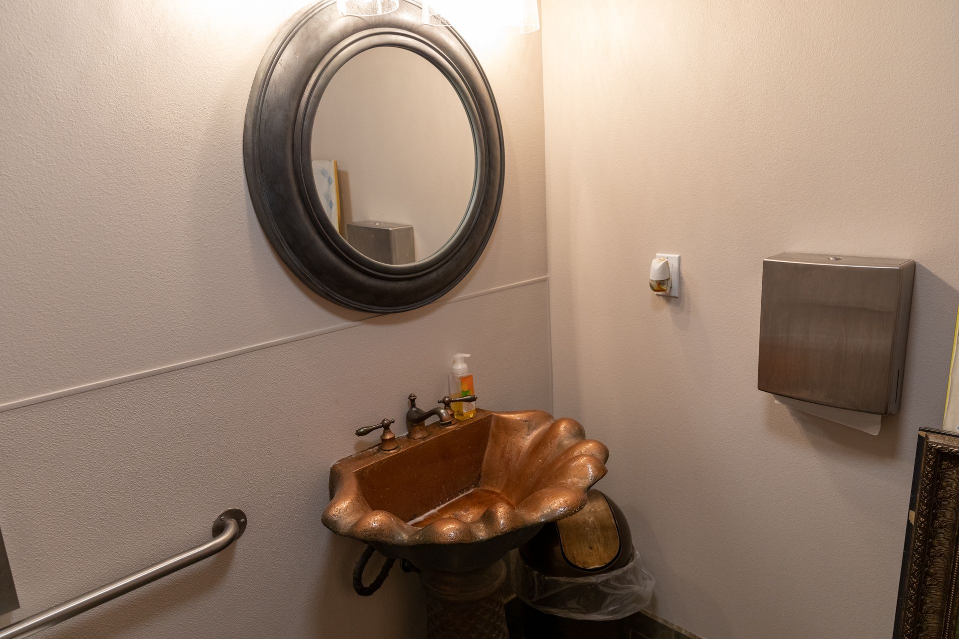 A bathroom with a copper sink and a mirror
