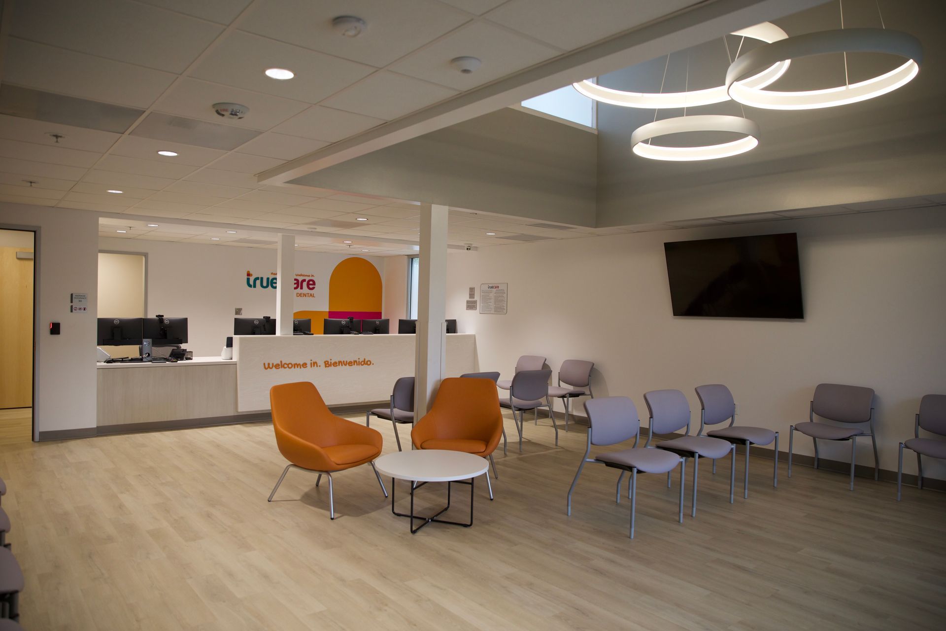 A waiting room with chairs , tables and a television.