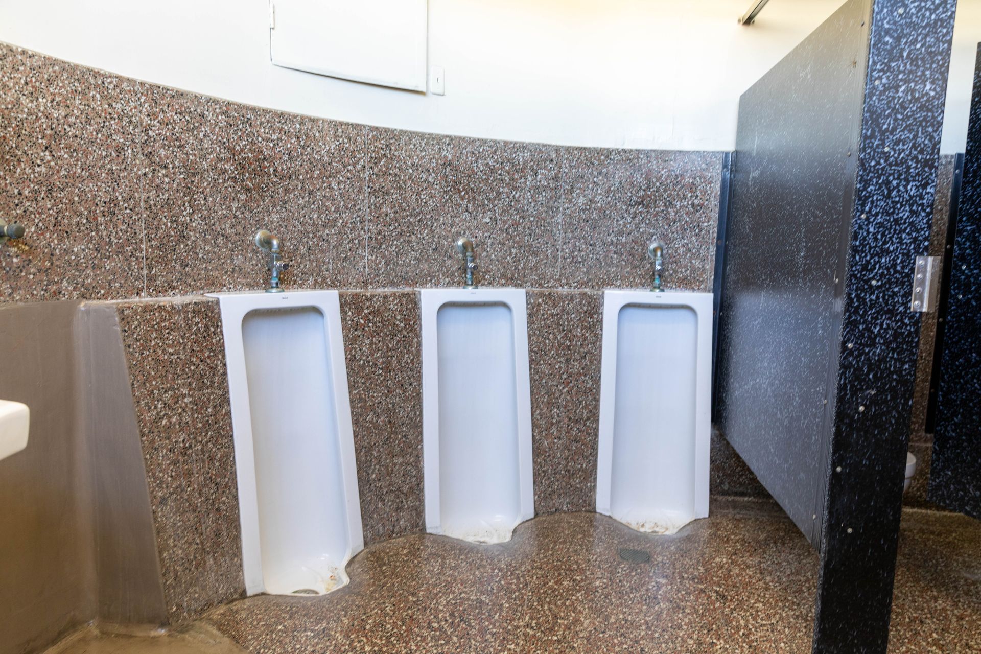 Three urinals are lined up in a public restroom.