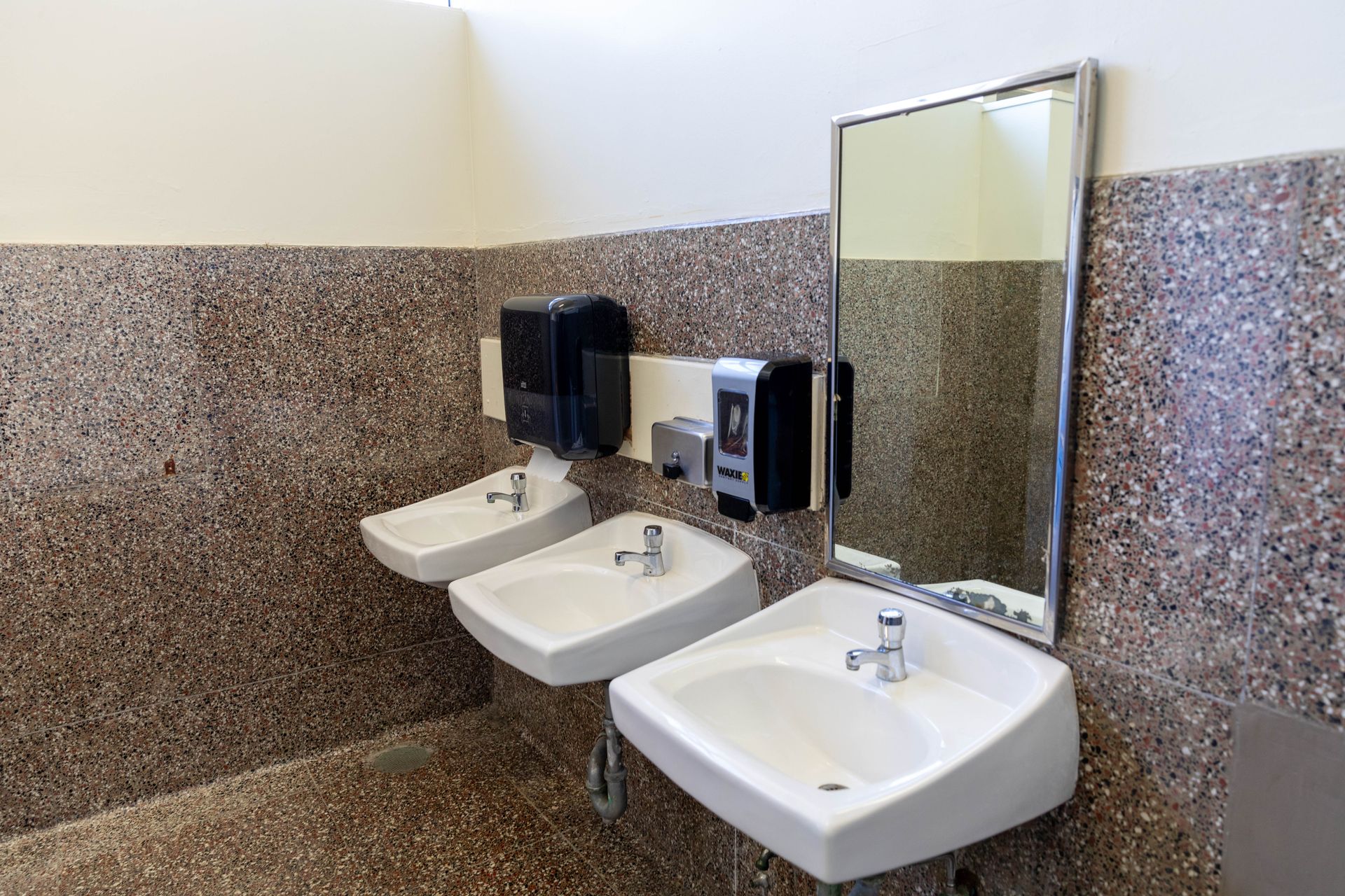 A bathroom with three sinks and a mirror.