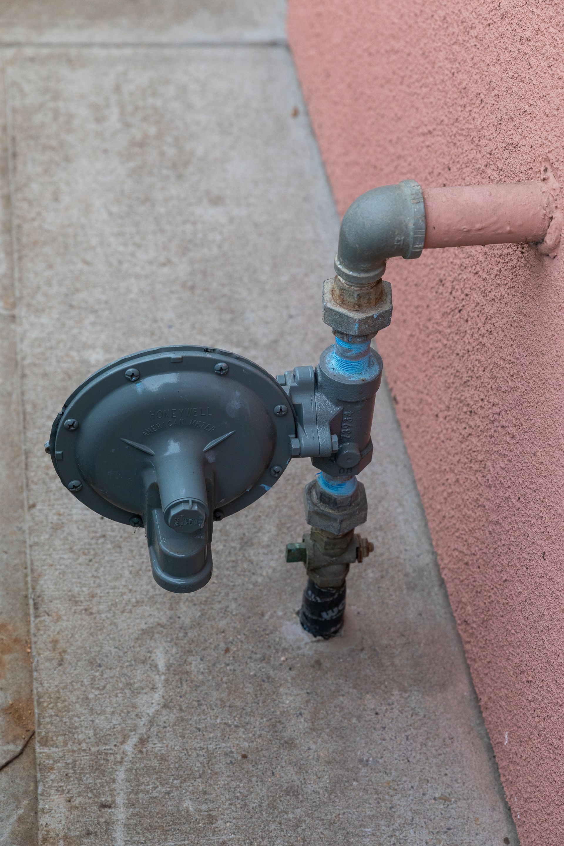 A gas meter is attached to a pipe on the side of a building.