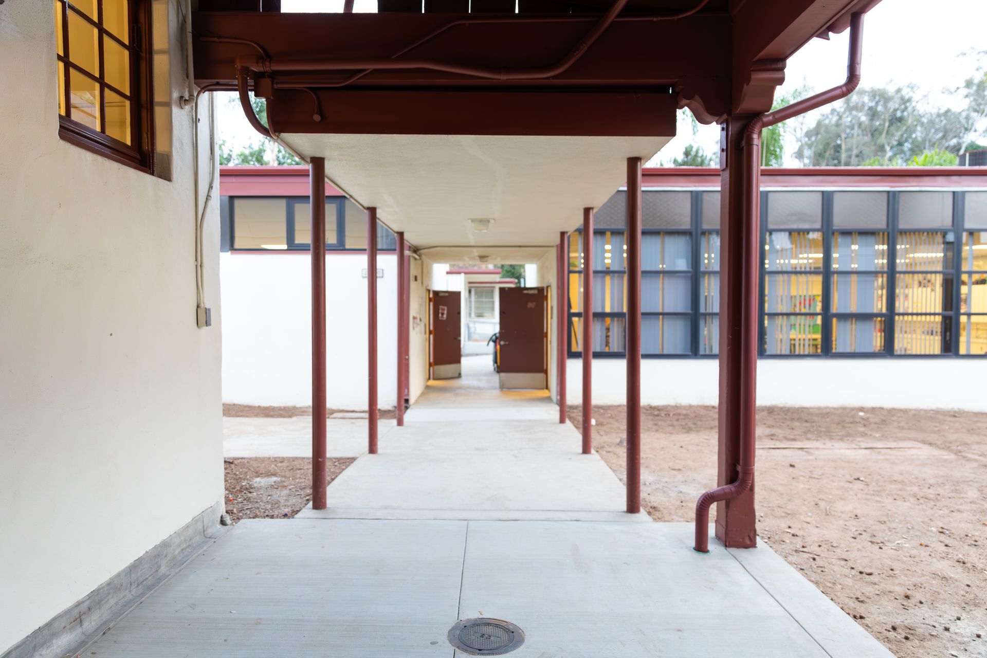A covered walkway between two buildings with a drain in the middle