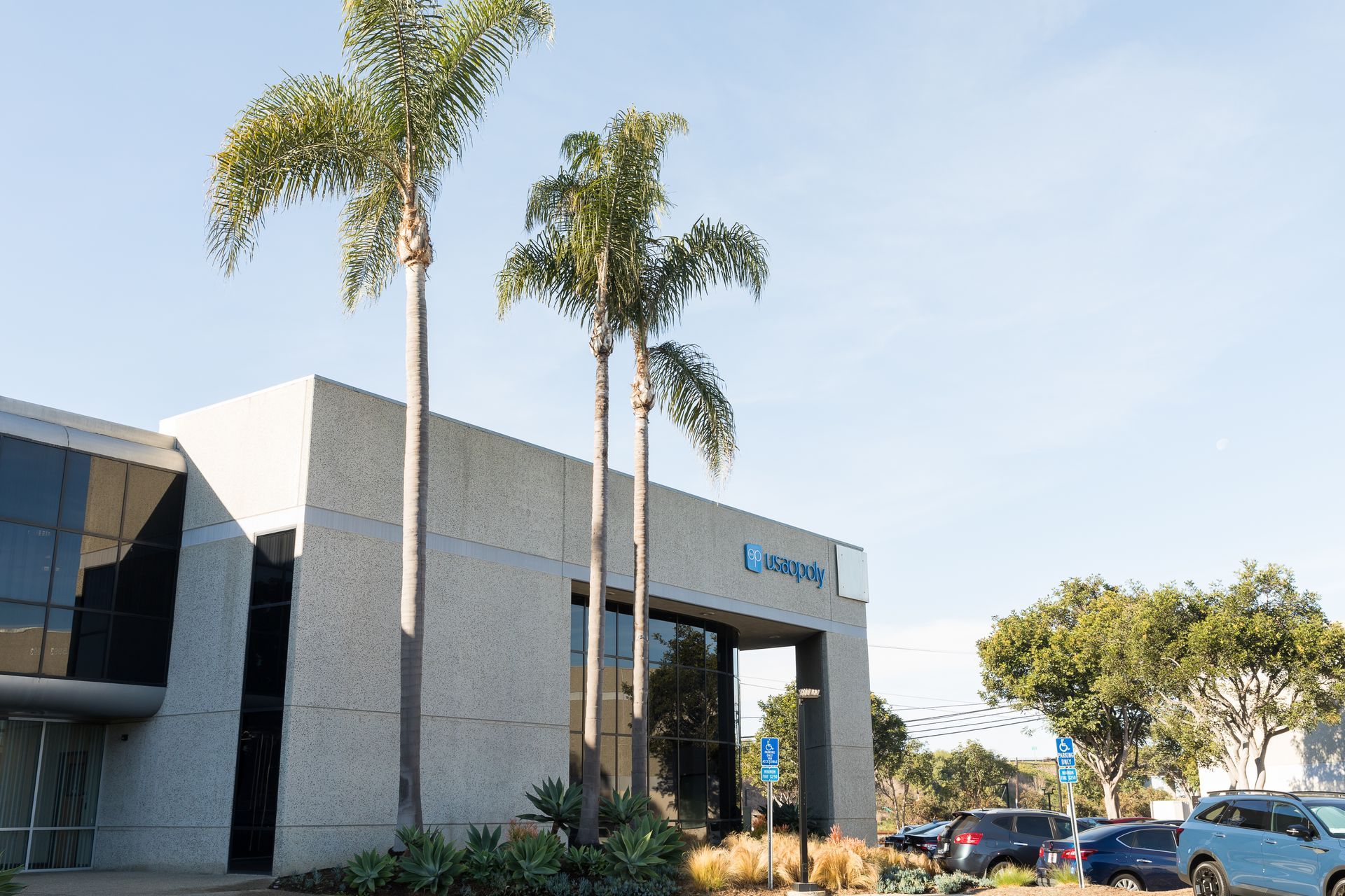 A building with palm trees in front of it and cars parked in front of it.