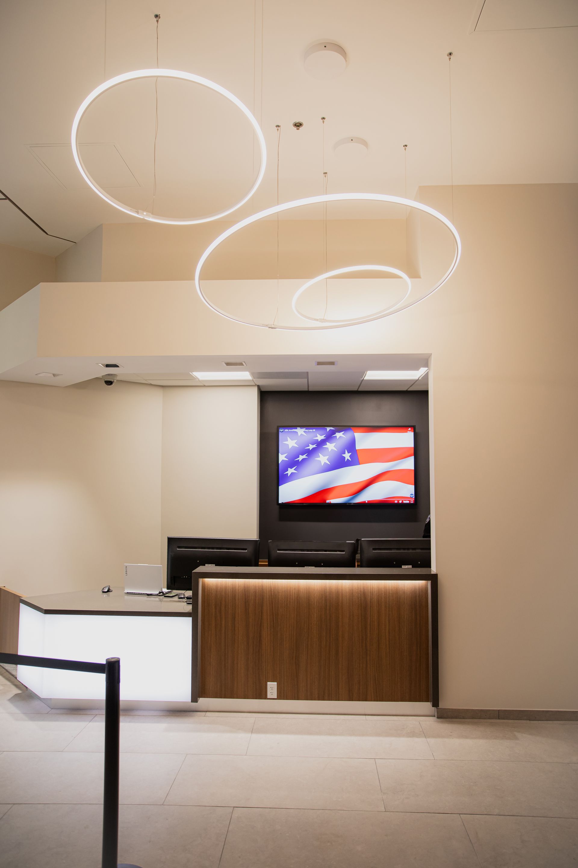 Hotel lobby desk with TV showing an American flag, lit by circular ceiling lights