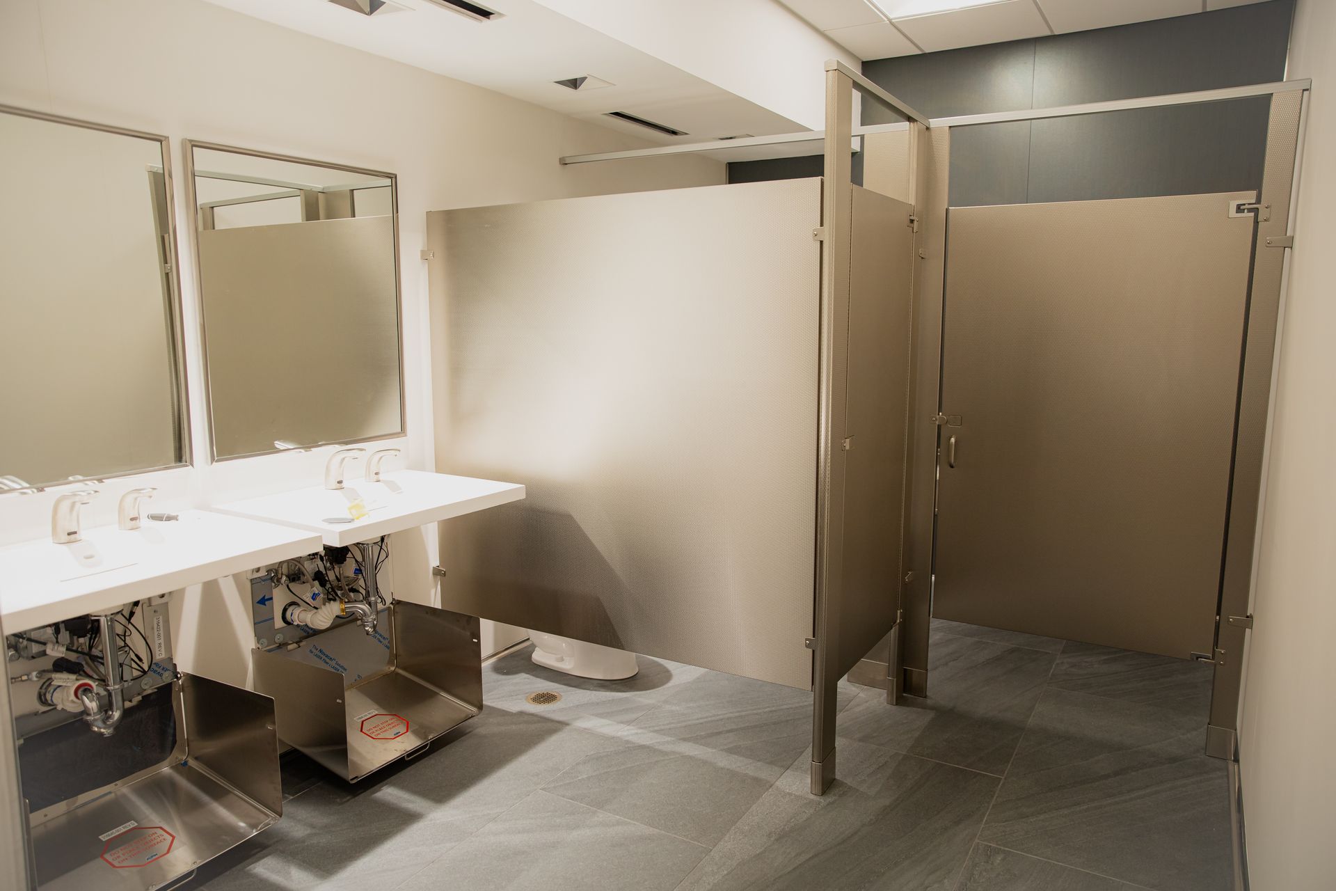 Public restroom with sinks, mirrors, stalls, and tiled floor