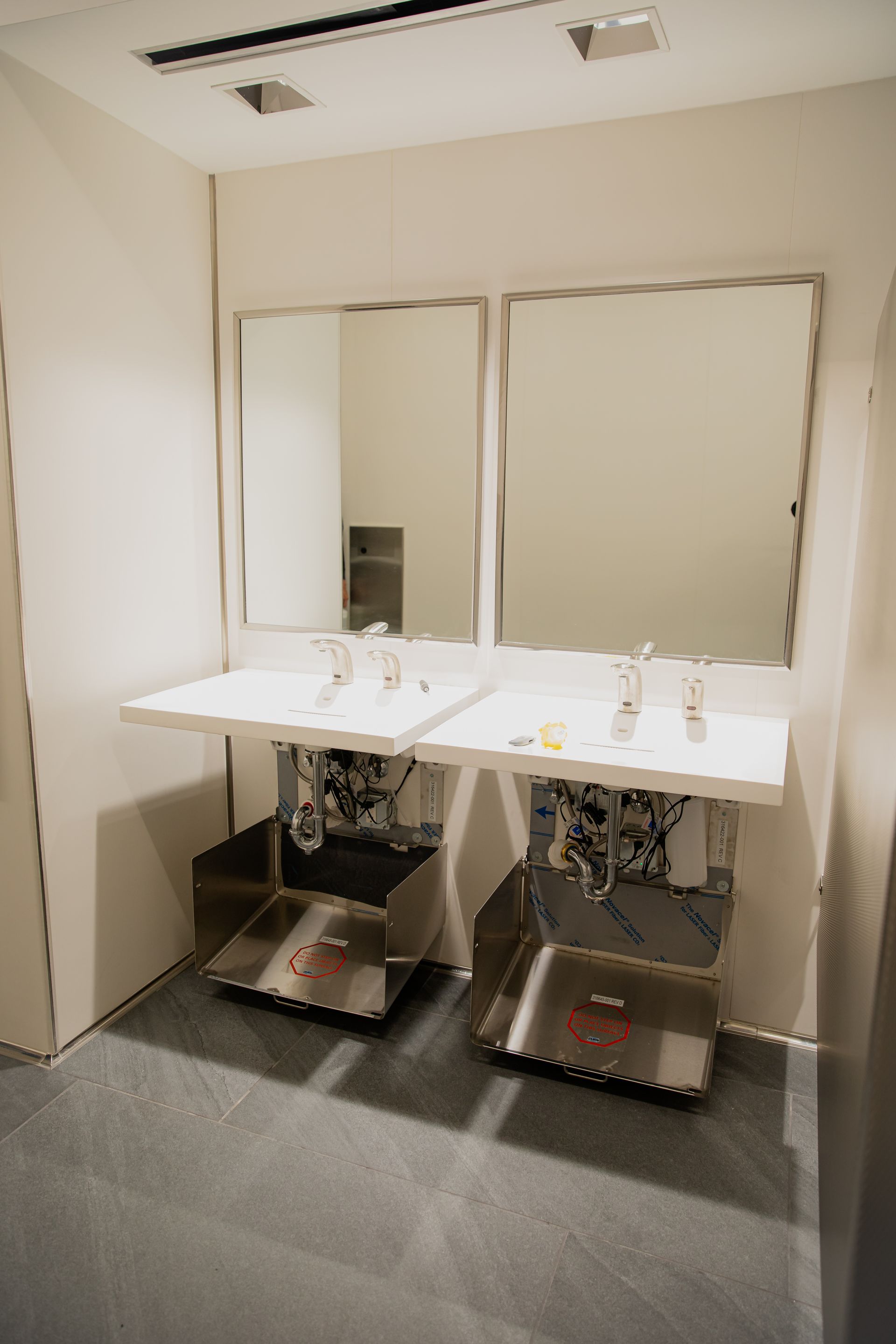 Two sinks with mirrors in a beige restroom changing area