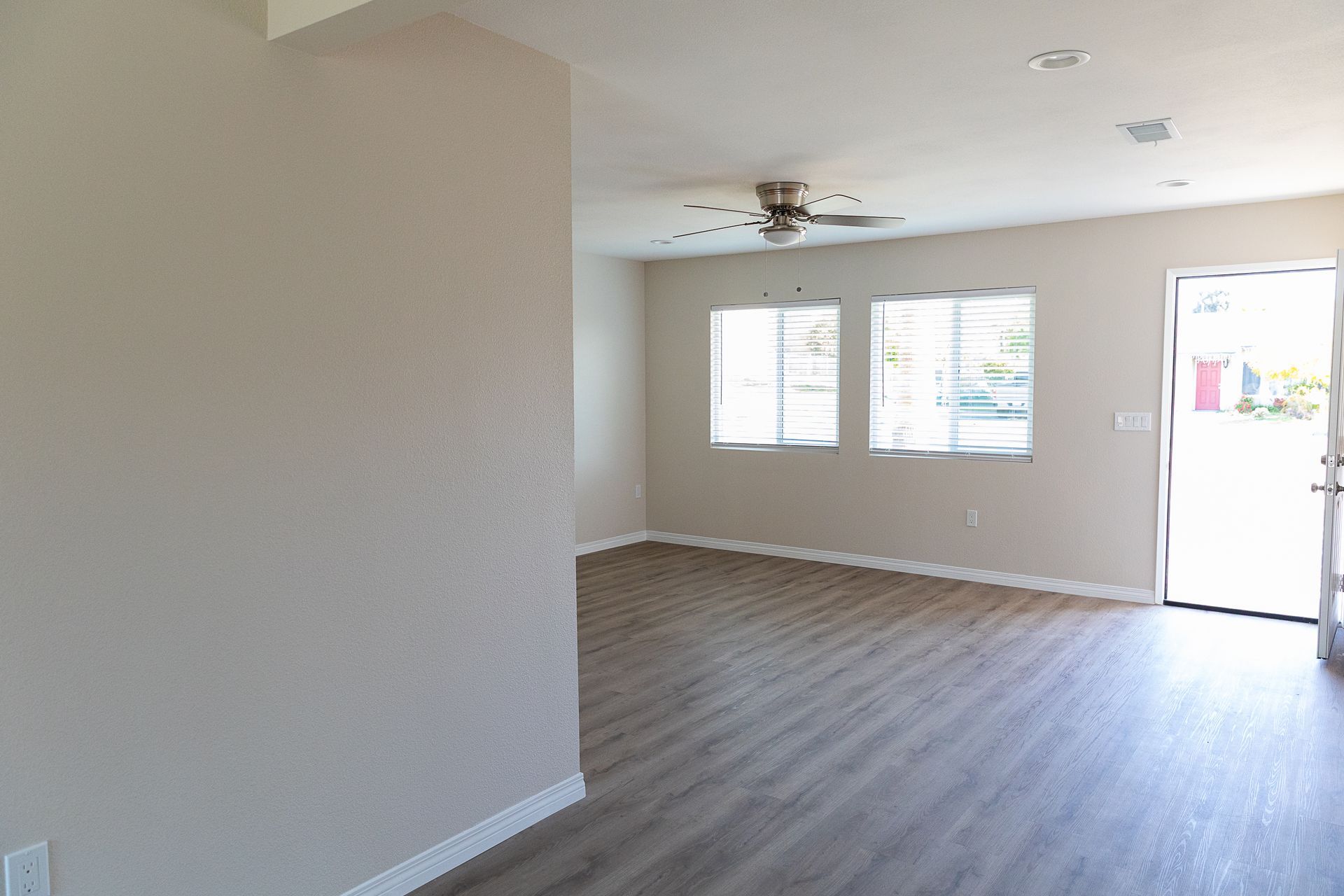 An empty living room with hardwood floors and a ceiling fan.