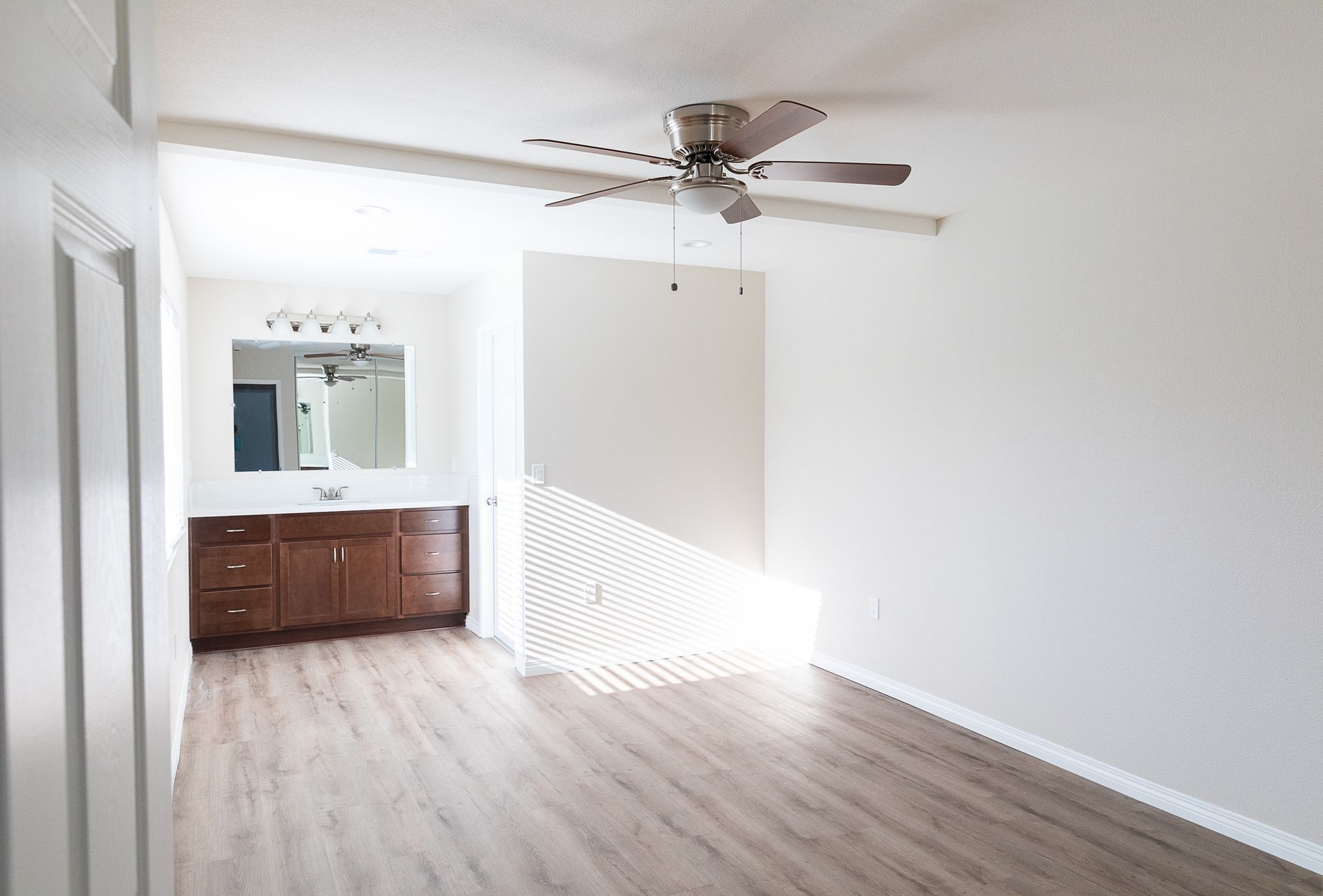 An empty room with a ceiling fan and a mirror