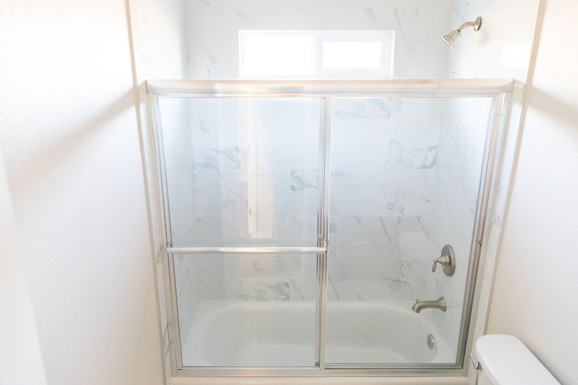 Small bathroom with frosted glass shower doors and a bathtub.