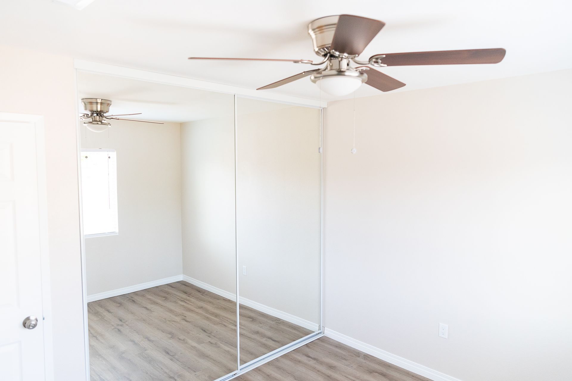 A bedroom with a ceiling fan and a large mirror.