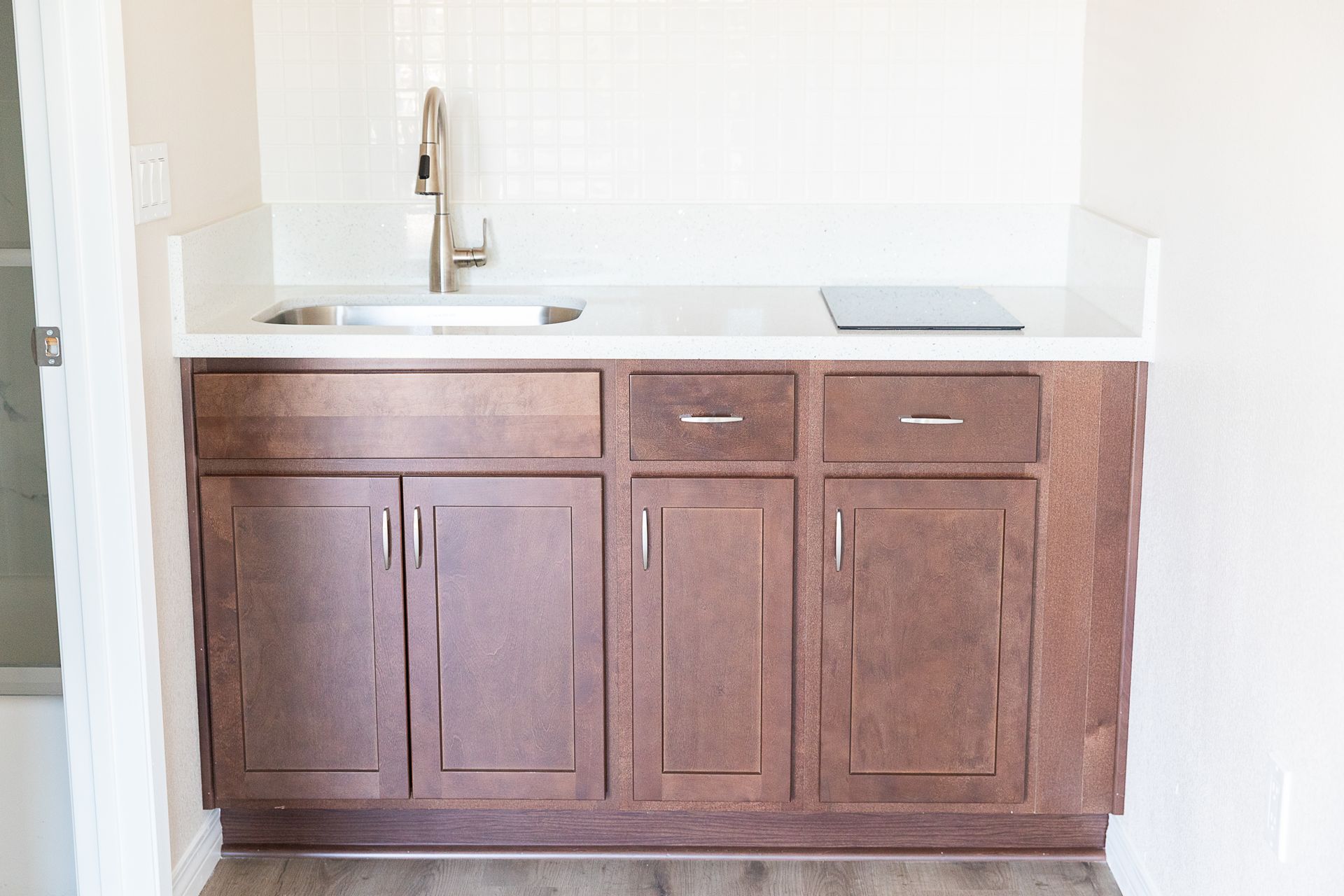 Wooden bathroom vanity with white countertop and sink in a bright alcove.