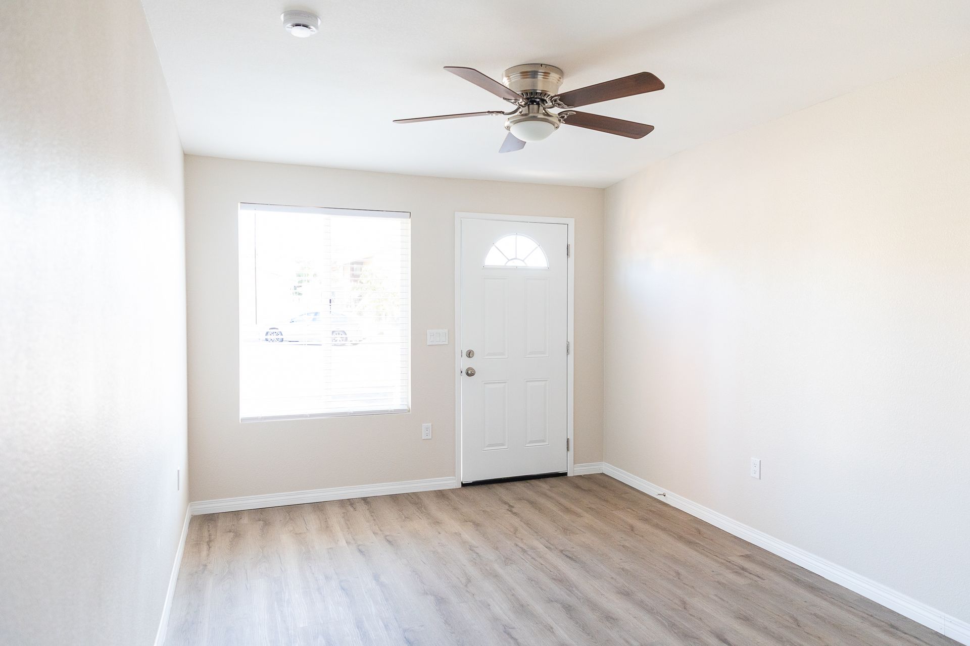 An empty room with a ceiling fan and a door.