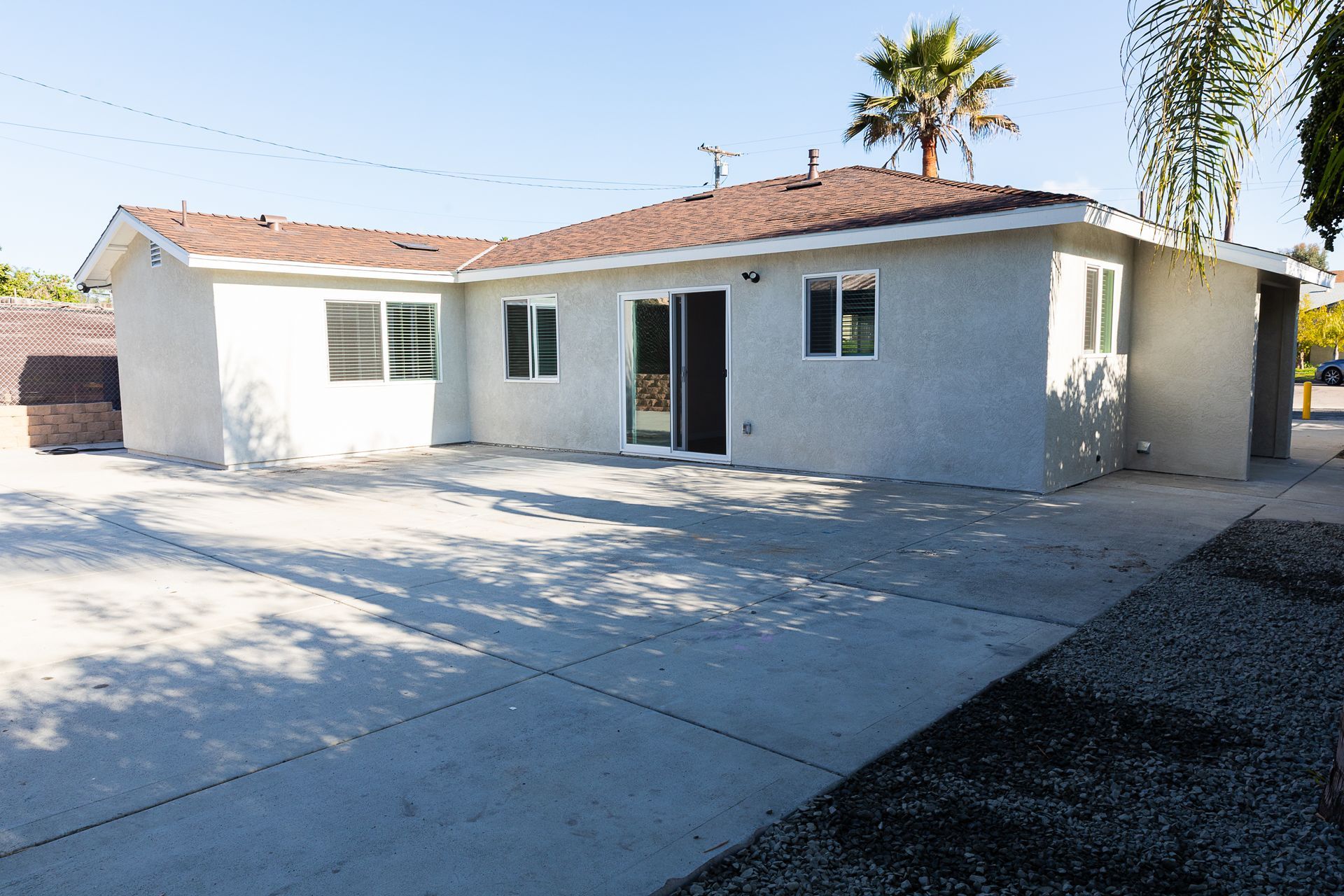 Single-story white stucco house with a red-tile roof and a large concrete driveway in front.