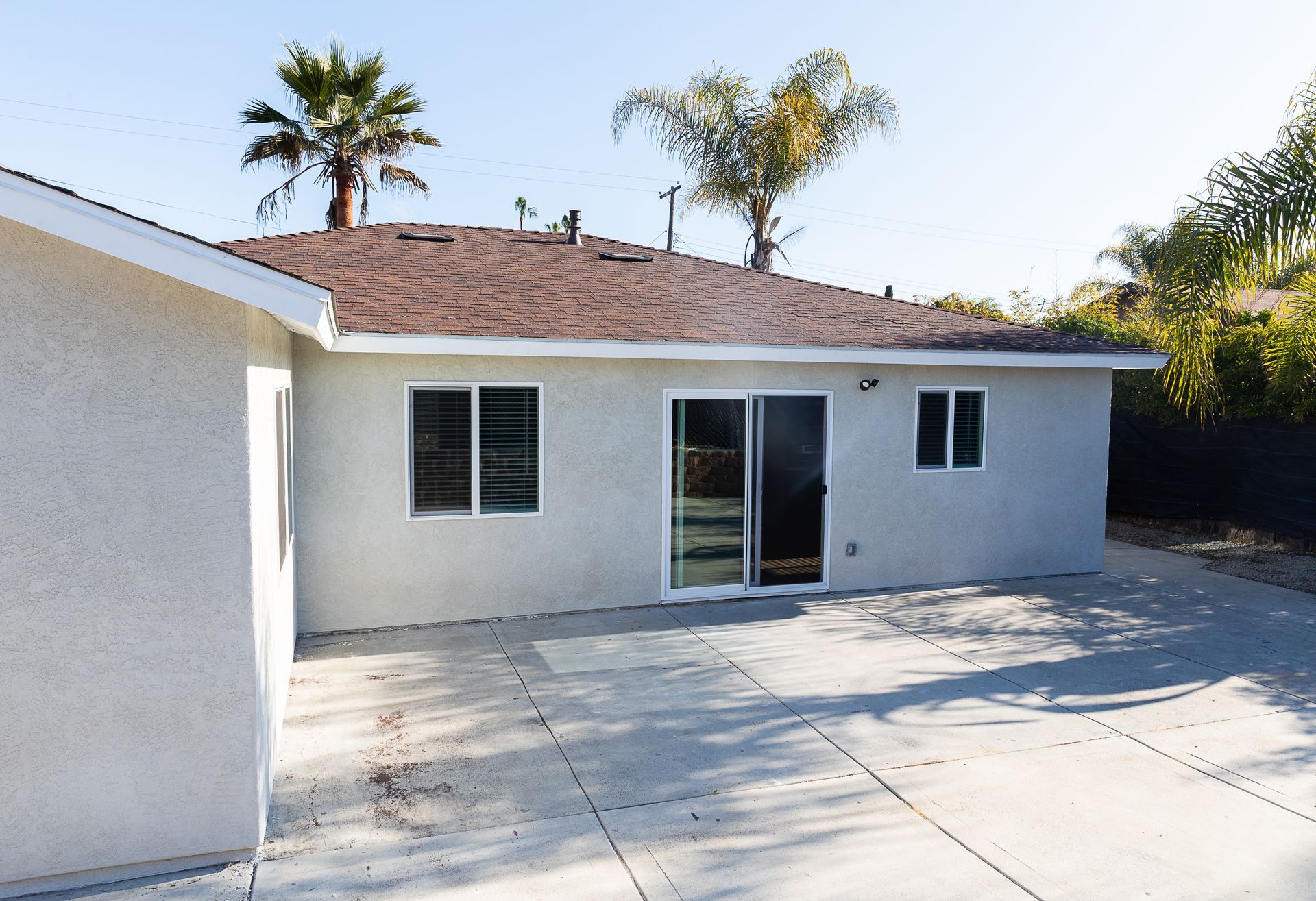 A white house with a brown roof and palm trees in the background