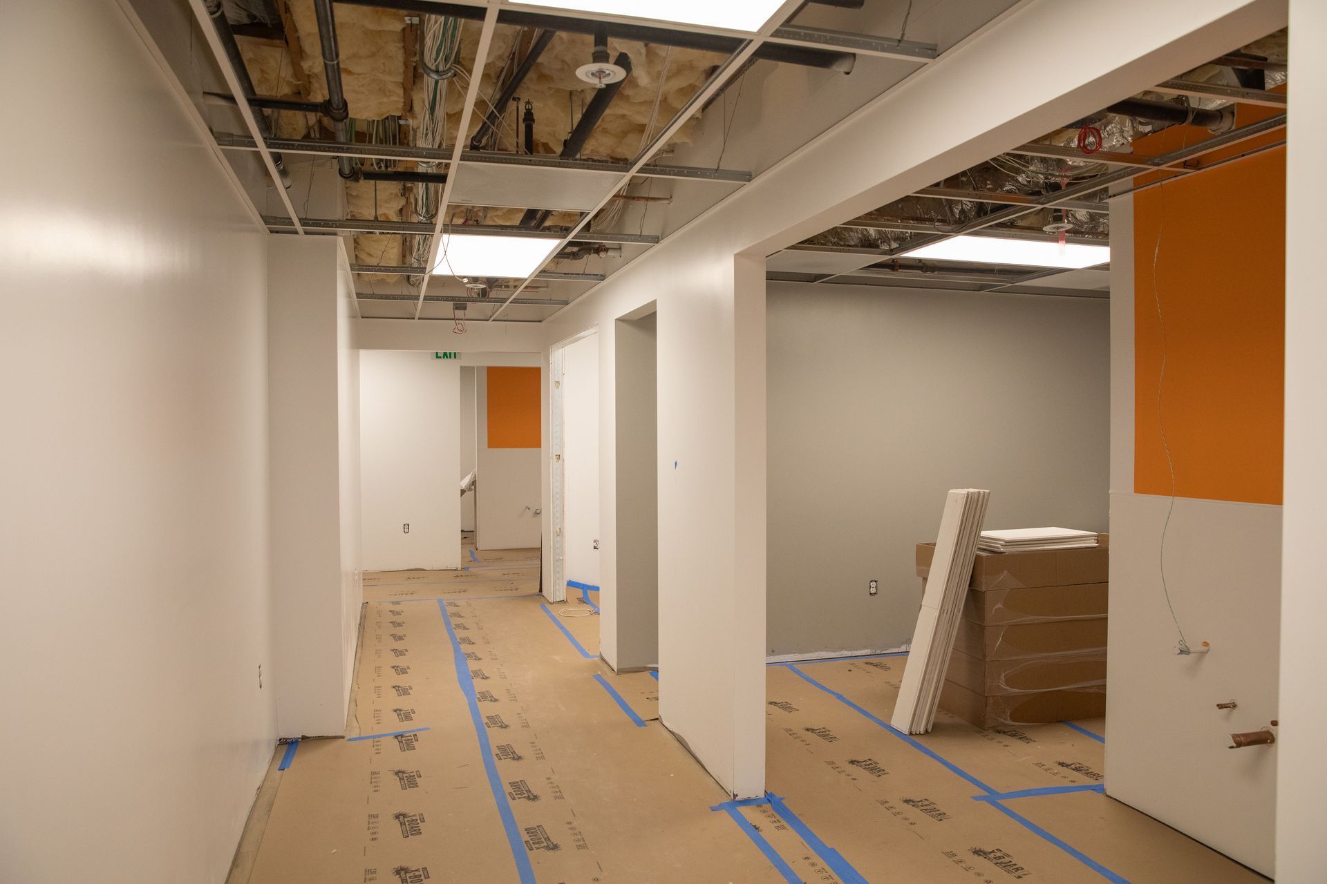 A long hallway with white walls and orange walls is being painted.
