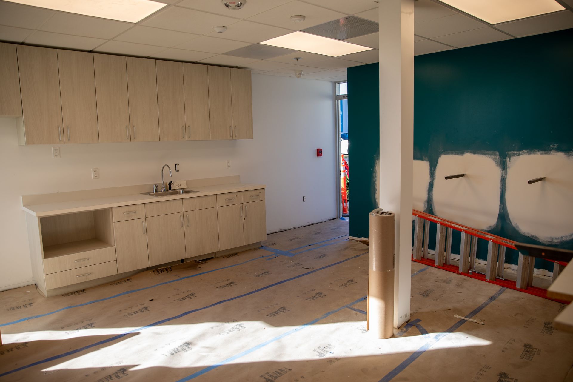 An empty room with a sink and a ladder in it