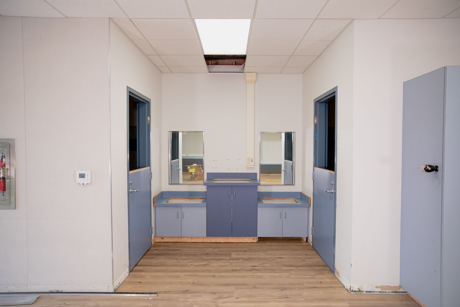 Empty office break room with blue cabinets, two sinks, and beige walls