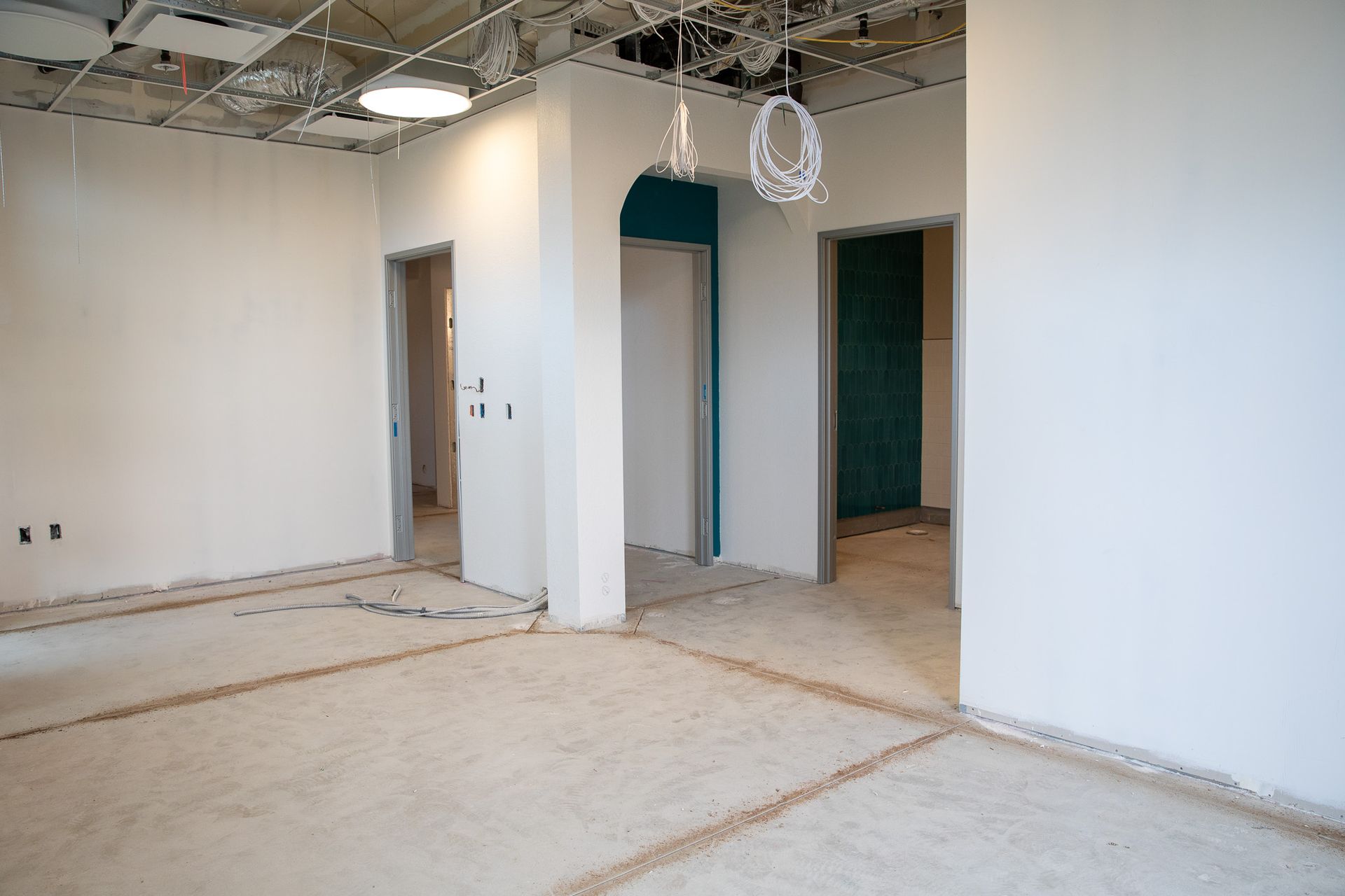 Empty unfinished interior room with exposed ceiling, white walls, and open doorways