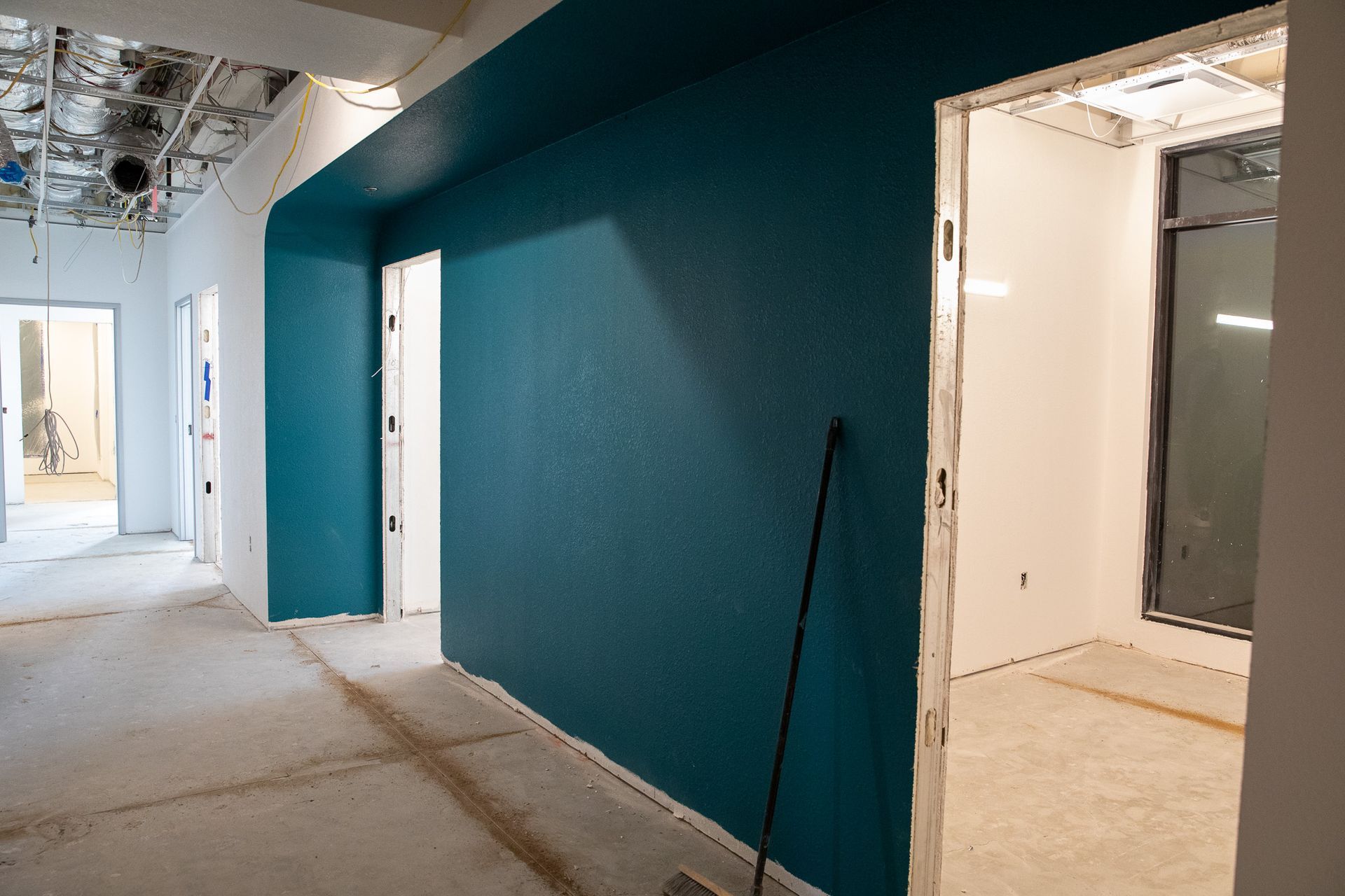 Empty hallway under construction with teal accent wall and open doorways