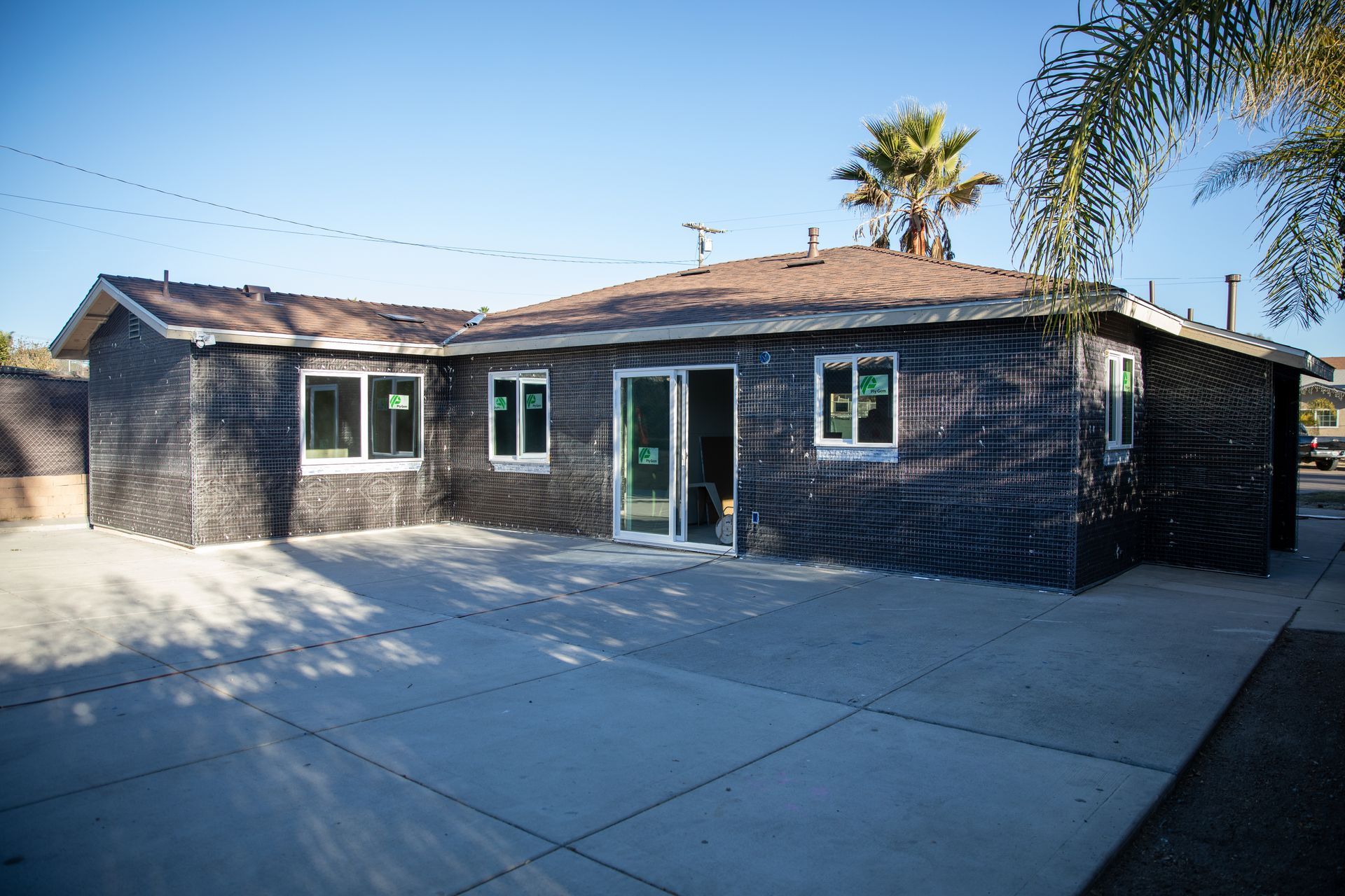 Single-story brick house with a large concrete driveway and palm trees in the background