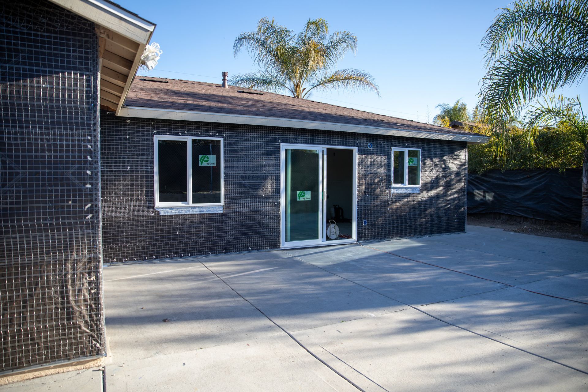 Backyard patio with a sliding glass door, small windows, and dark shingle siding on a house