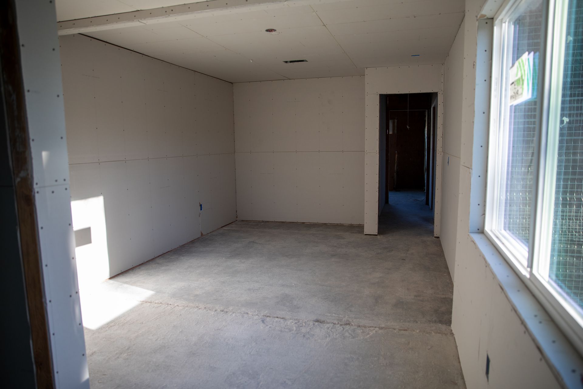An empty room with a concrete floor and two windows