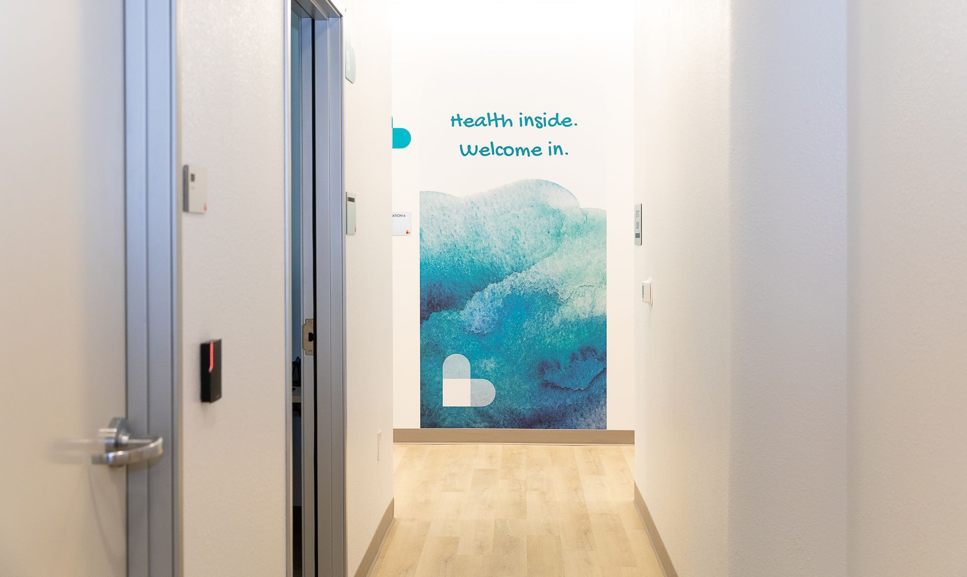 A hallway with a door and a painting on the wall.