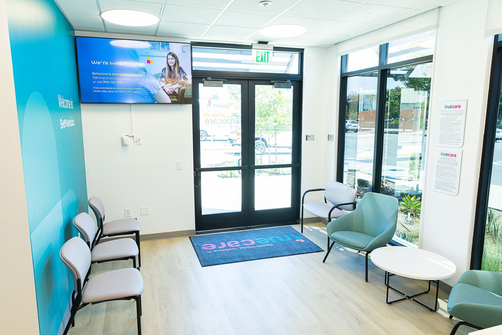 Bright, modern waiting room with chairs, glass doors, and blue accents near the entrance.