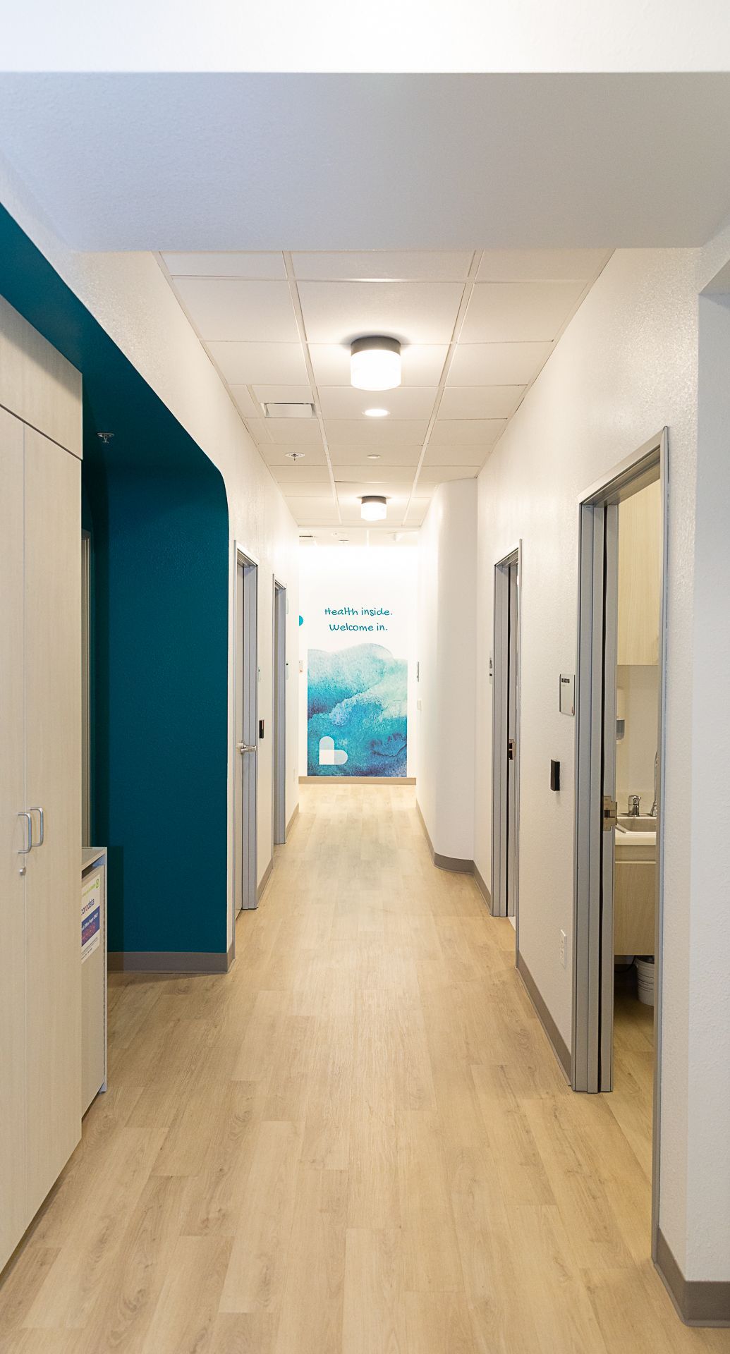 A long hallway with wooden floors and blue walls in a hospital.