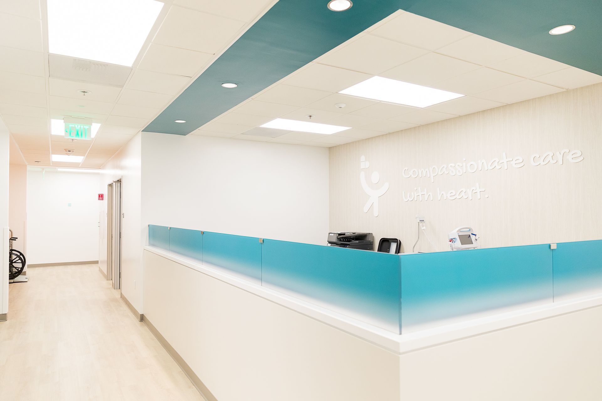 A hospital lobby with a blue counter and a white wall.