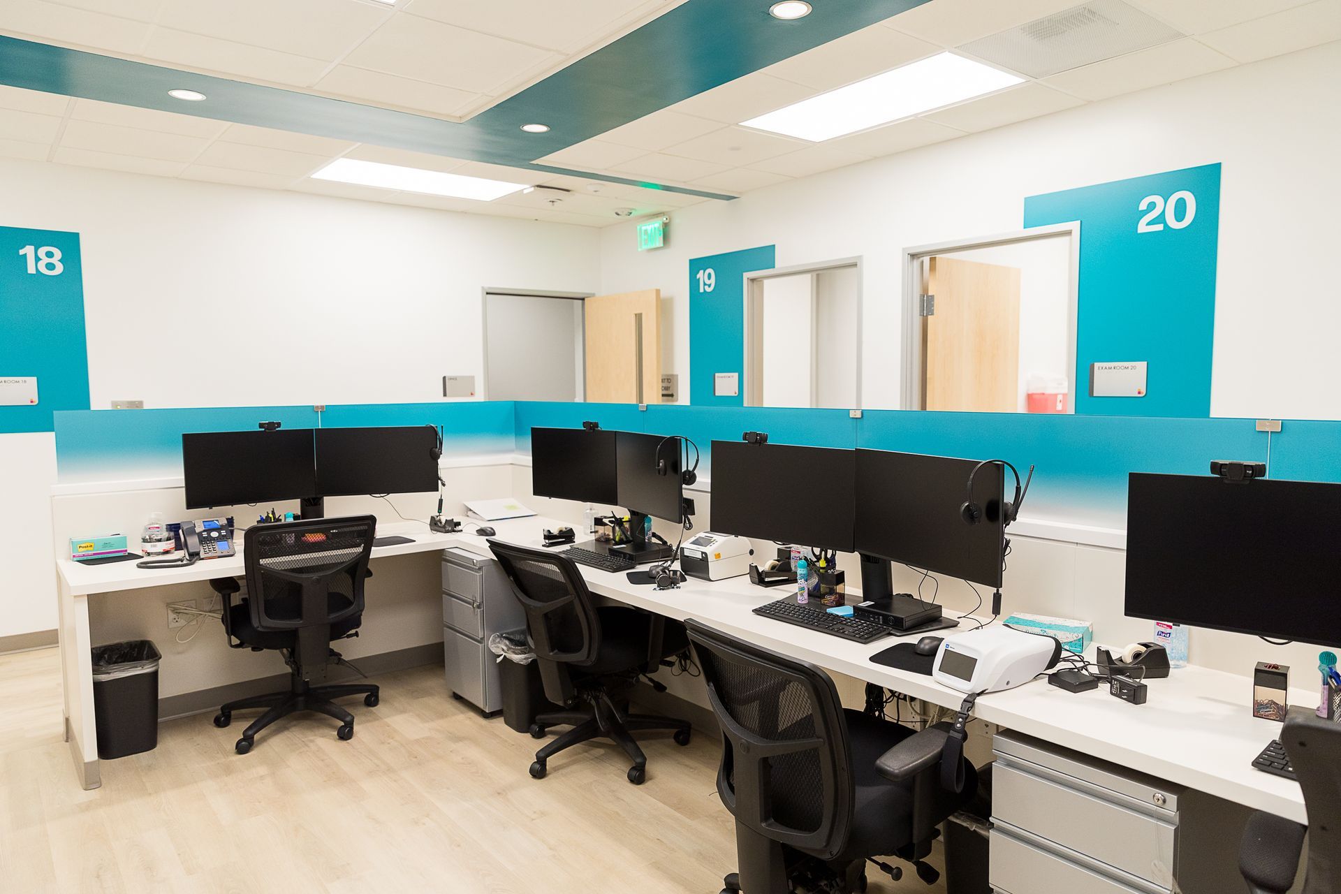 A row of desks with computers and chairs in an office.