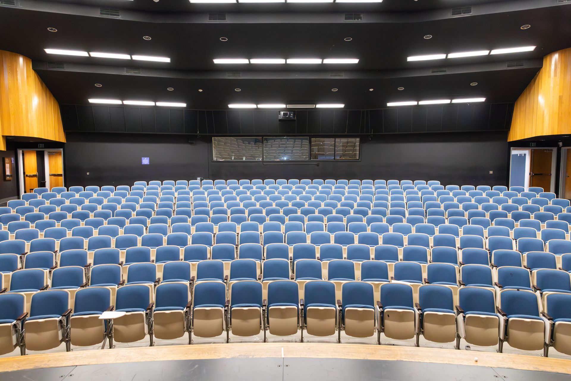 Empty auditorium with rows of blue seats and a stage in front